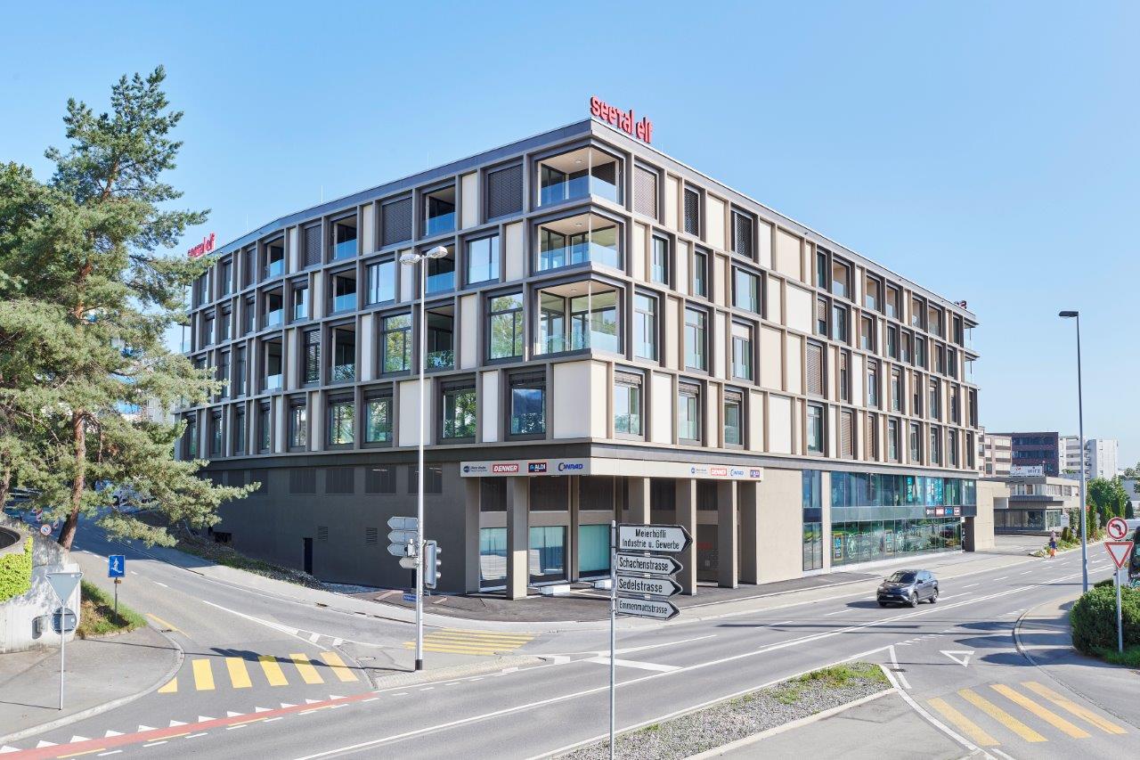 Modern multi-story building with glass windows, balconies, and a rooftop sign reading 'seetal'.