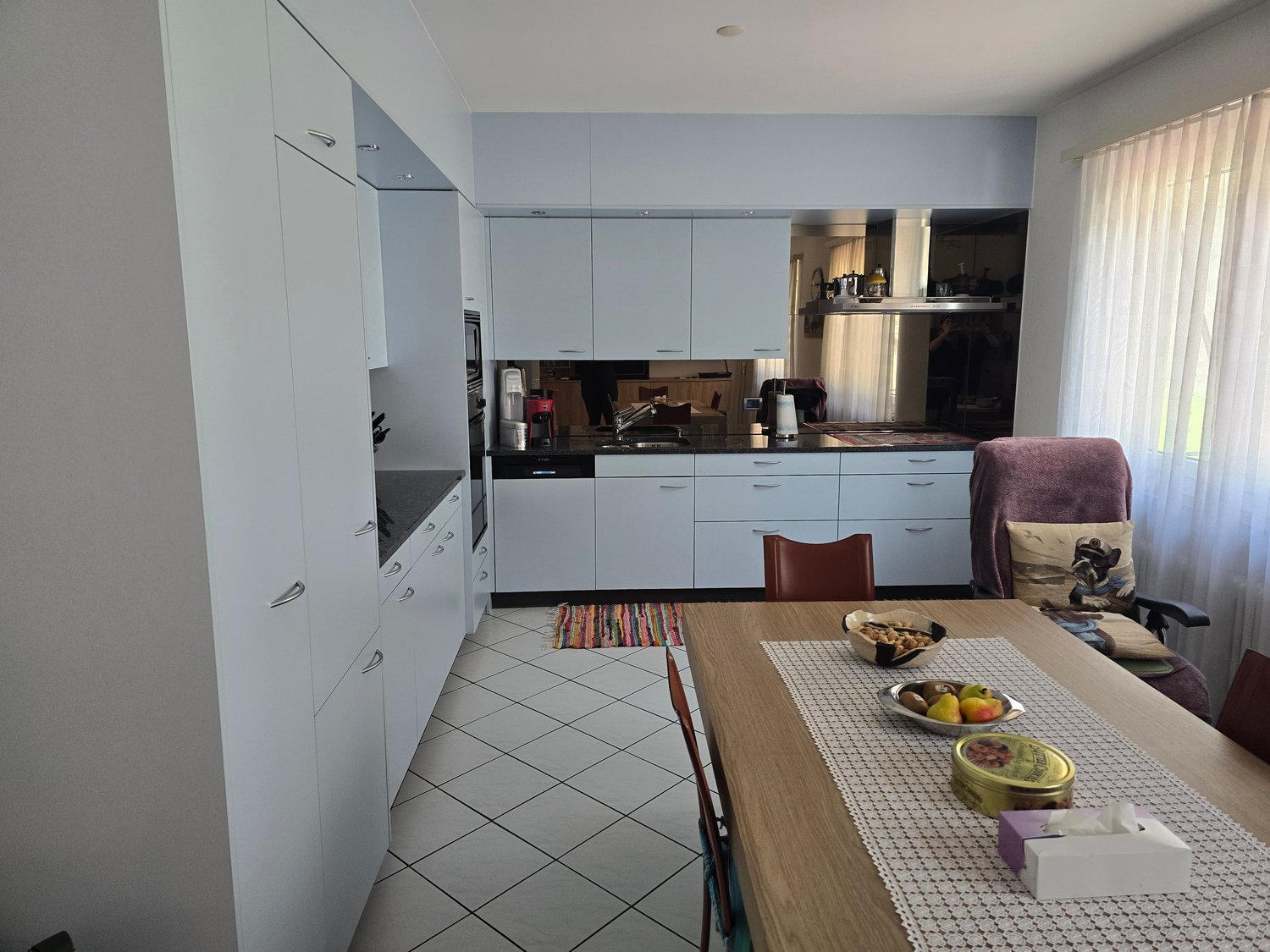 modern kitchen with white cabinets, black countertops, stainless steel appliances, dining table with decorative items