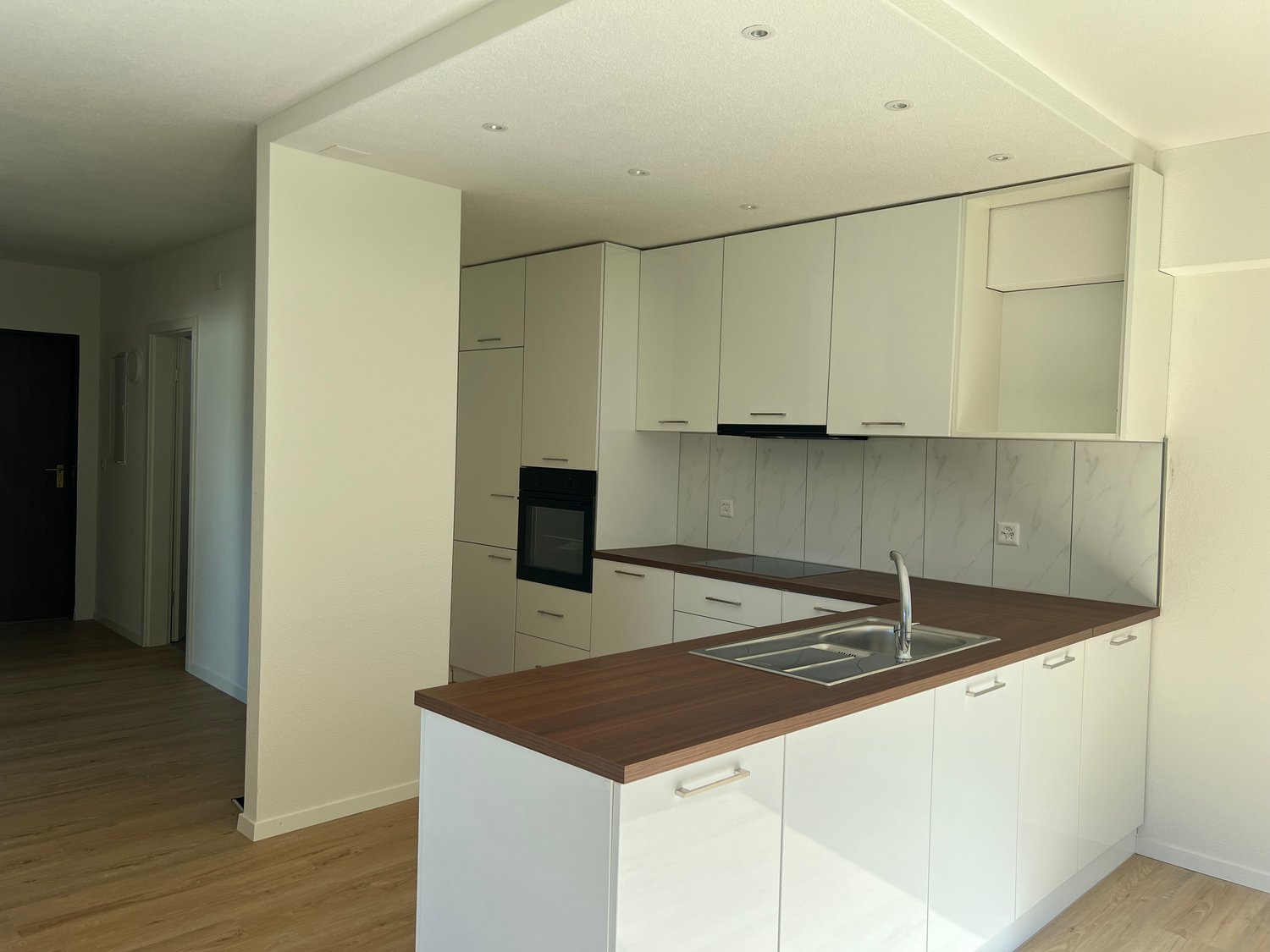 Modern kitchen with white cabinets, wooden countertops, built-in oven, and a dishwasher