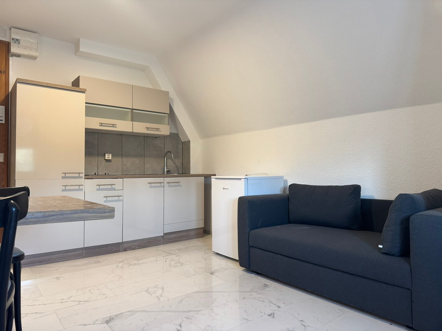 Small kitchen with integrated appliances, tile flooring, modern furniture, sofa bed