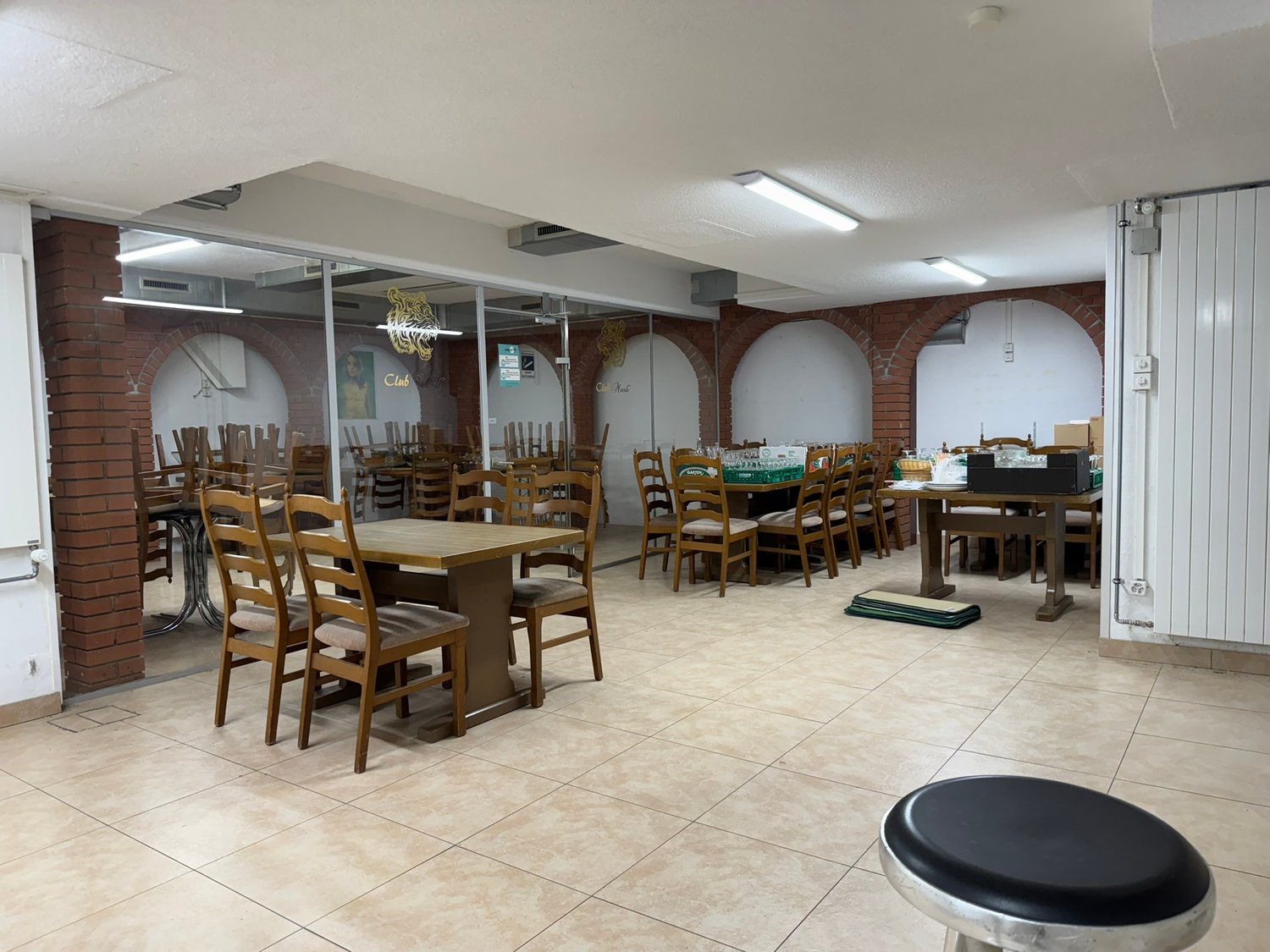 Wooden tables and chairs, tiled floor, brick wall, glass wall, tables in another room