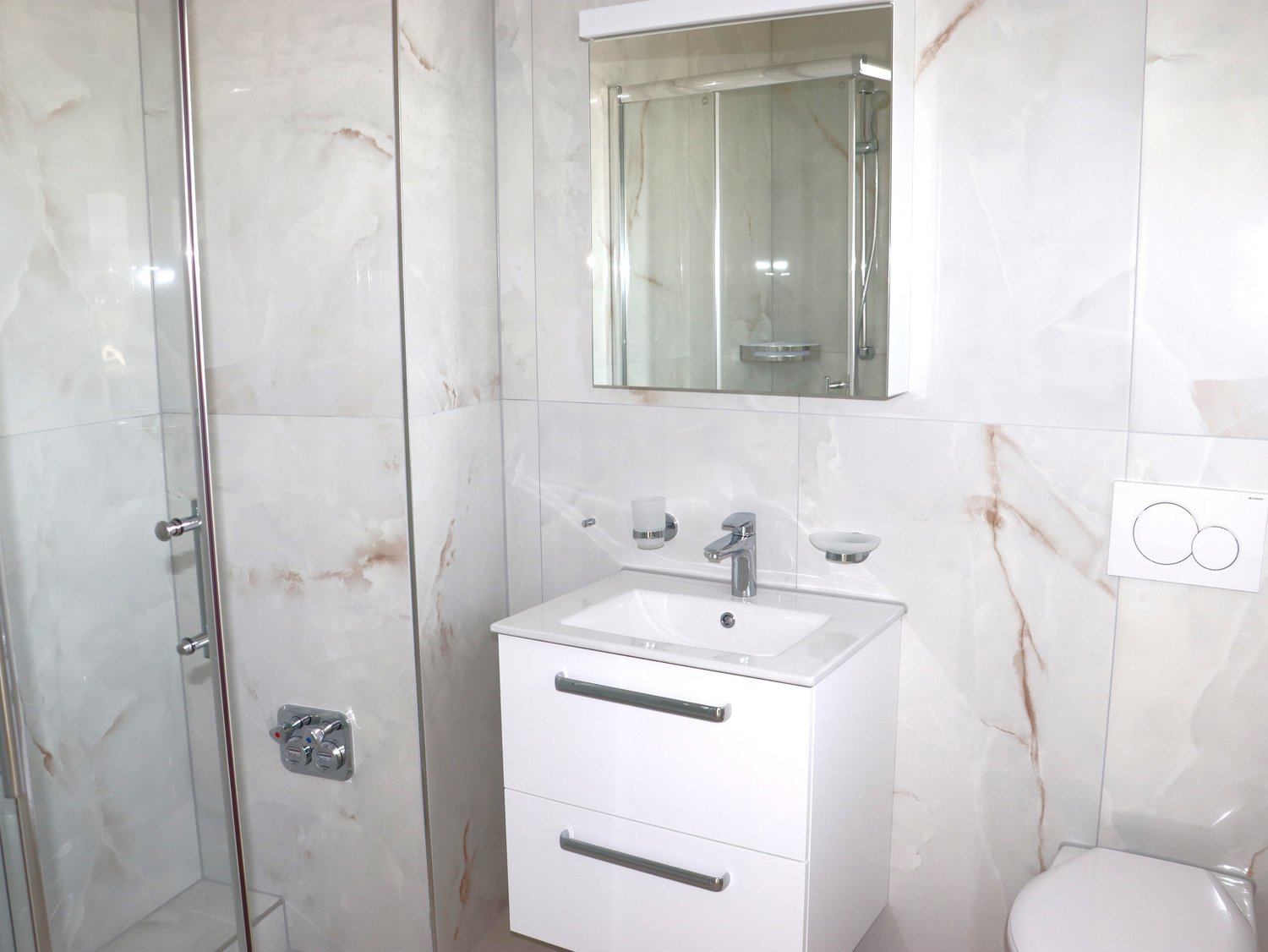 modern white bathroom with white marble walls, shower enclosure, sink with faucet, mirror, toilet