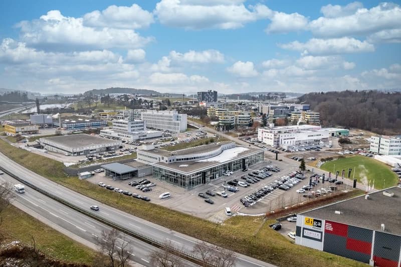 Building complex, multiple buildings, large parking lot, highway in front, green surroundings