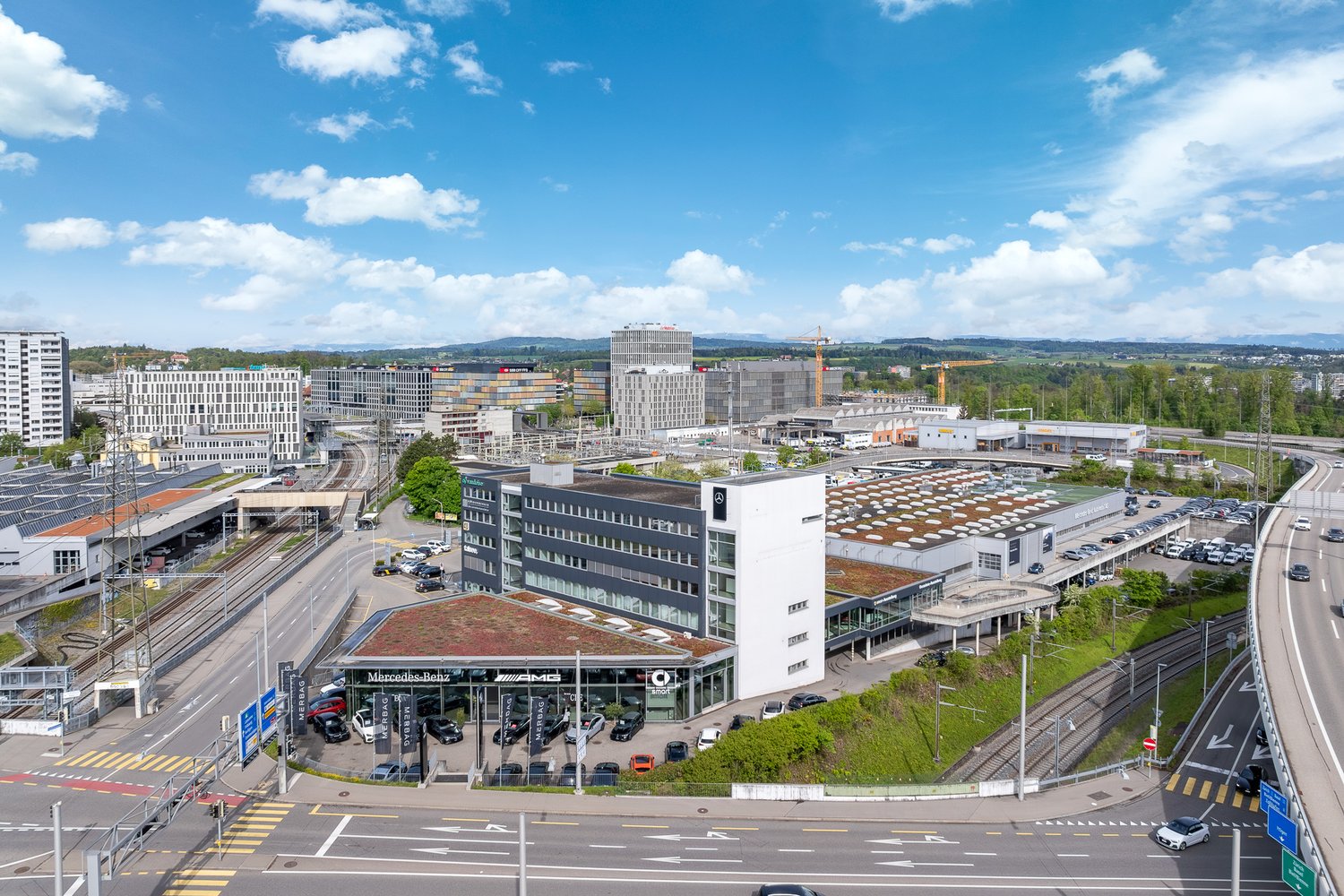 commercial complex with multiple buildings, green roof on parts of the building, multiple cars parked