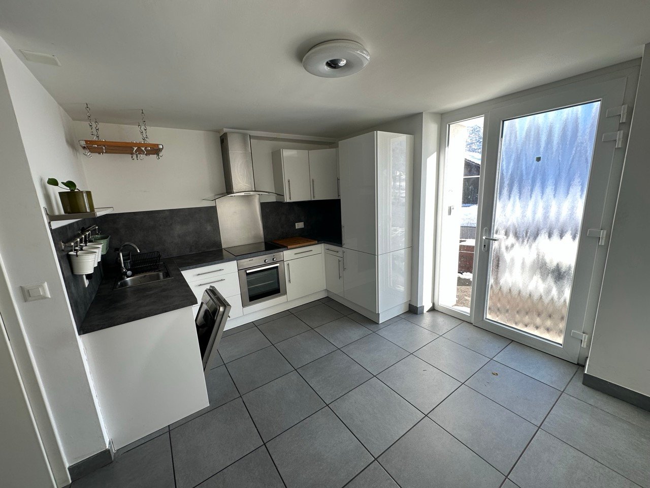 modern kitchen, white cabinetry, grey tile flooring, granite countertops, stainless steel appliances, under cabinet lighting