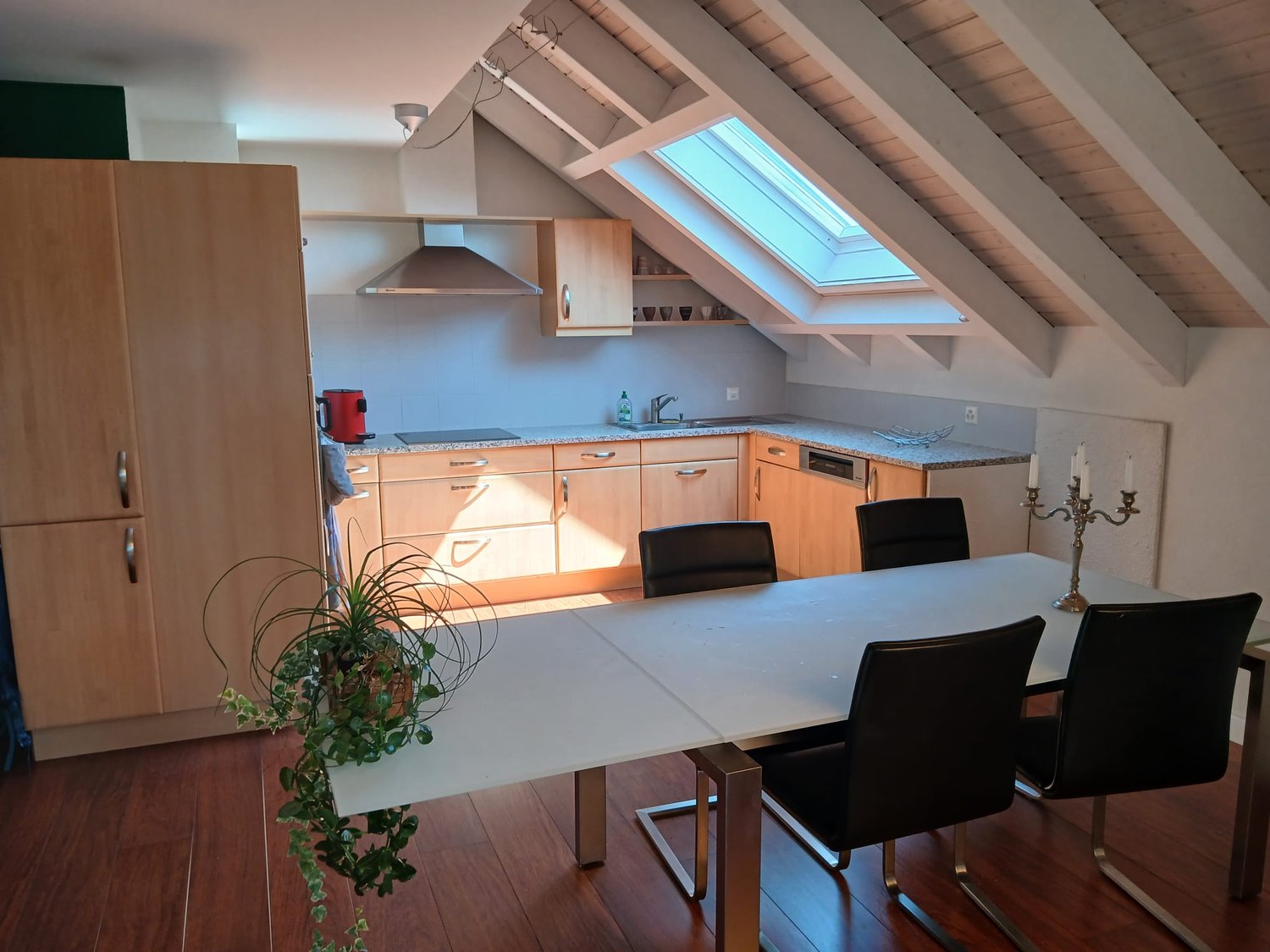 kitchen with dining table, cabinets, wooden floor, loft, skylight, potted plant