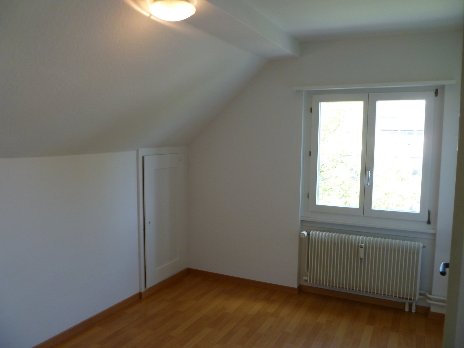 white walls, white ceiling, wooden floor, white door, window with white frame
