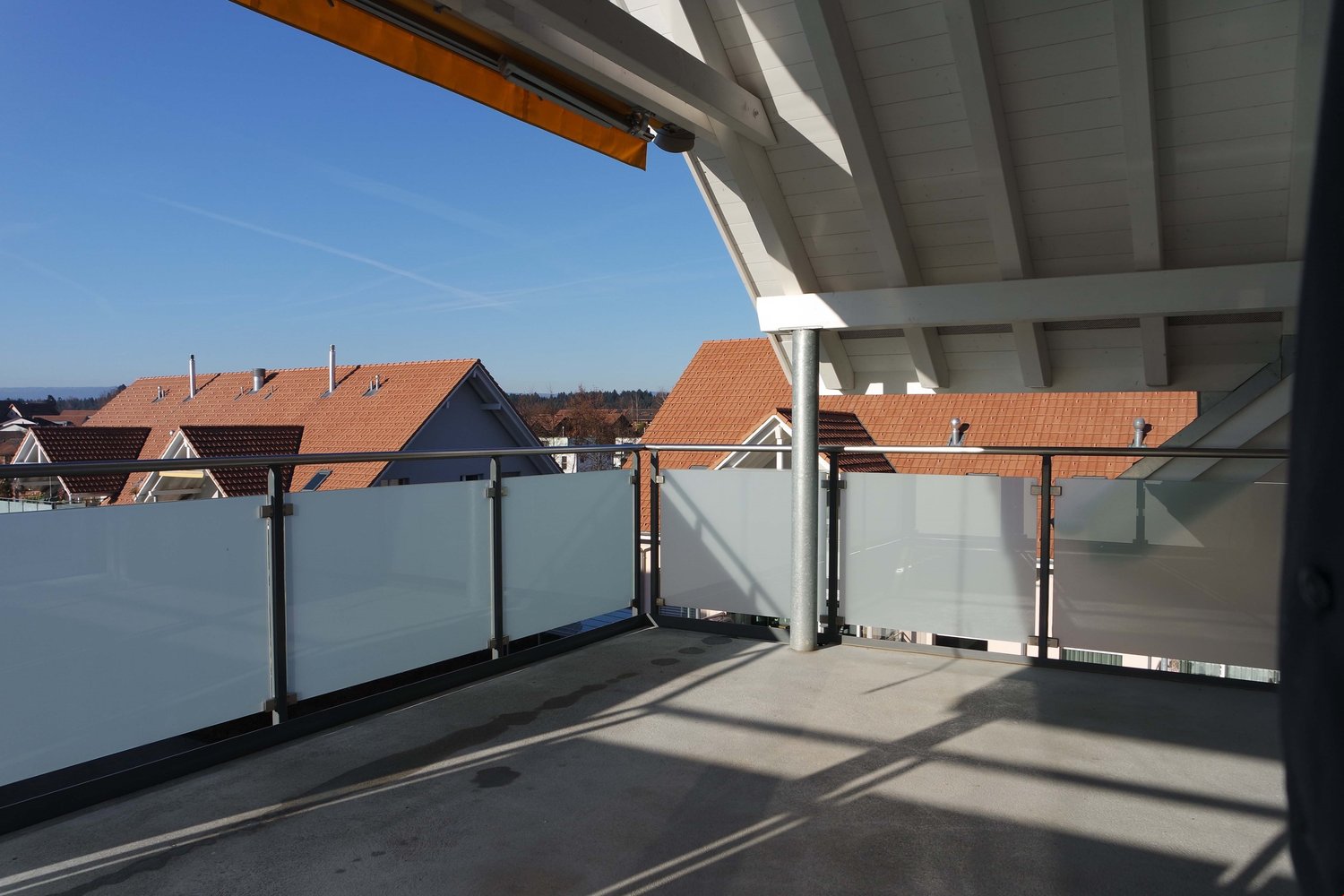 Terrace with metal railings, overlooking neighborhood houses, glass partition walls
