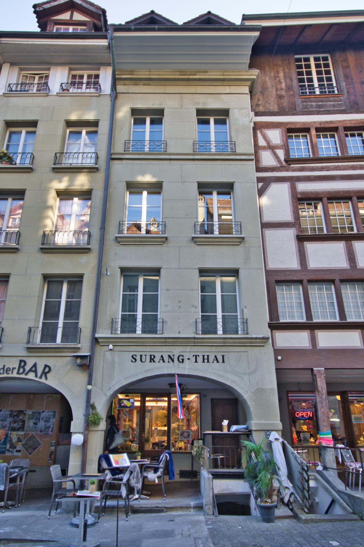 multi-story commercial building, facade has windows, metal railings, store front, outdoor seating area