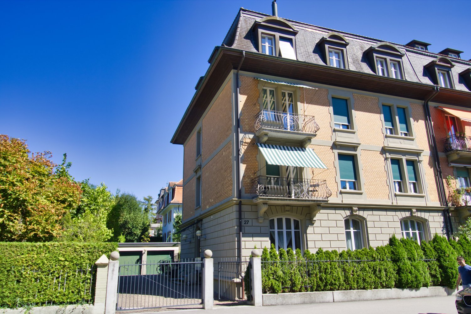 three story house, brick exterior, balconies, gated driveway, fenced hedges