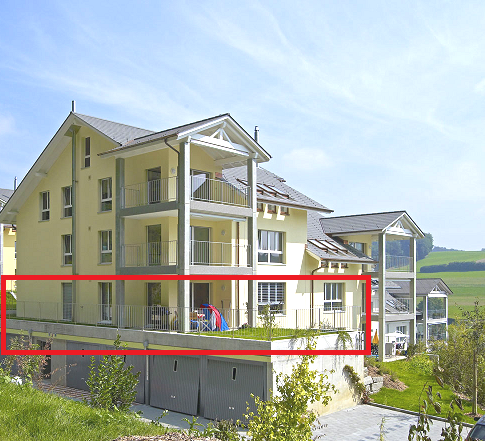 Yellow two-story house with three garages, gray roof, large balcony on the second floor, two entrances, green grass on the balcony, surrounded by trees and grass, rural background
