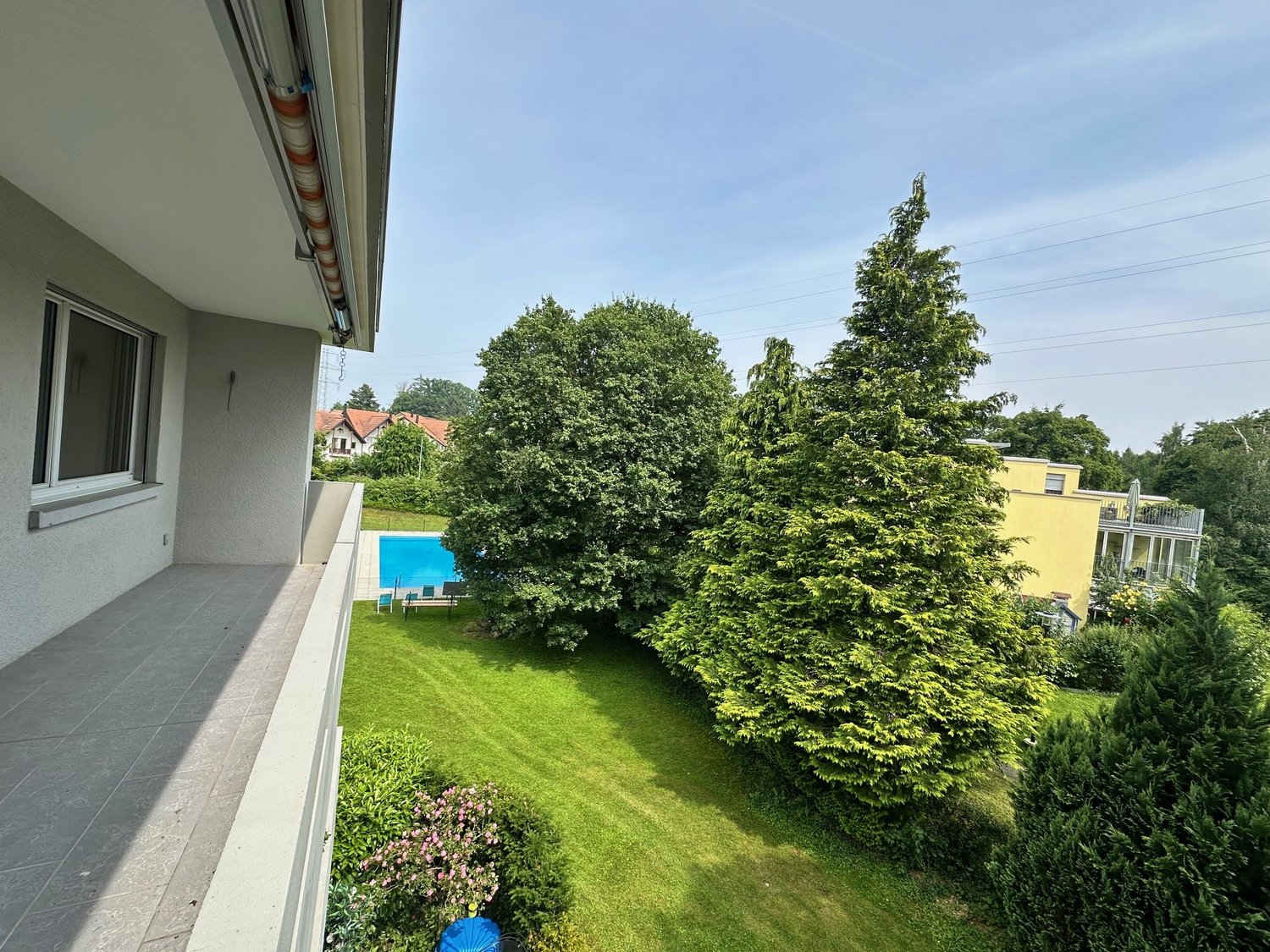 2-story house with a swimming pool in the backyard, surrounded by lush greenery including trees and a well-maintained lawn.