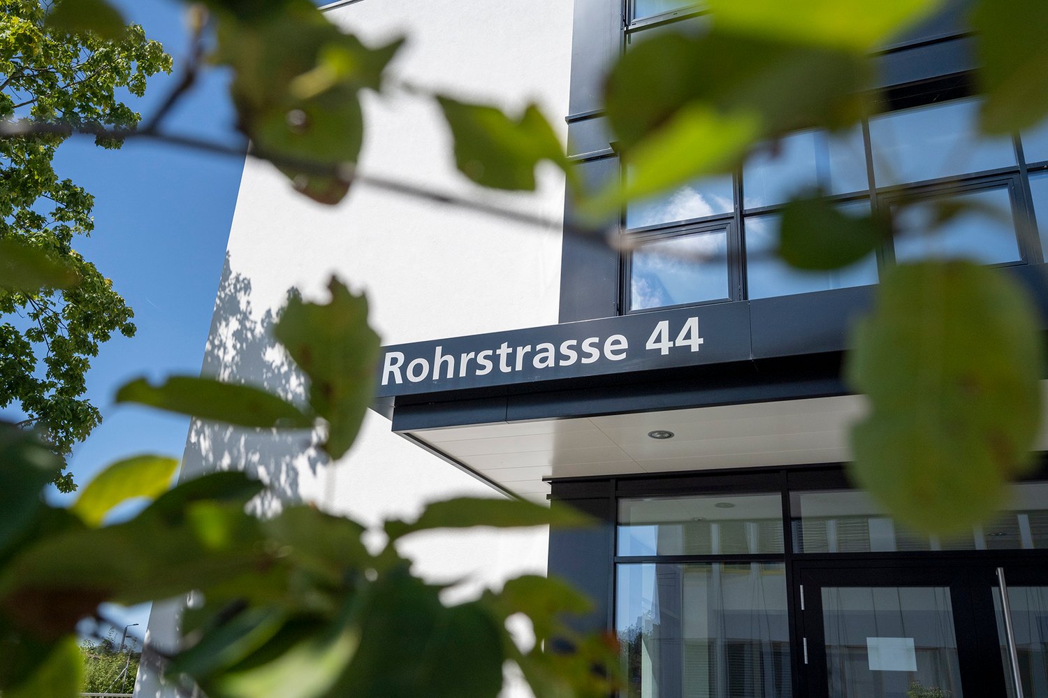 modern building, white exterior, glass windows, metal railing, entrance doors, number 44