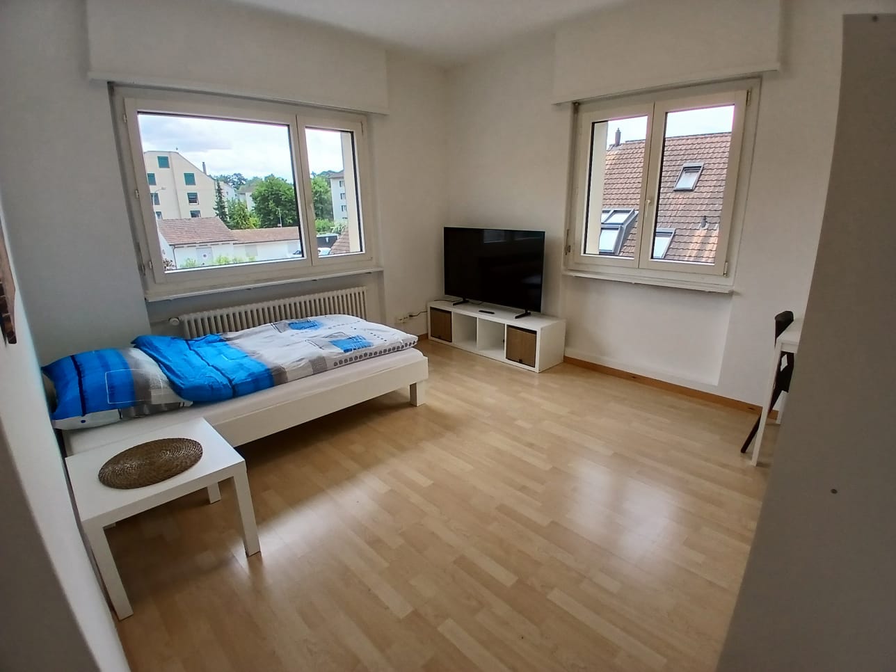 single bed, windows, wooden floor, white walls, TV on stand, white side table