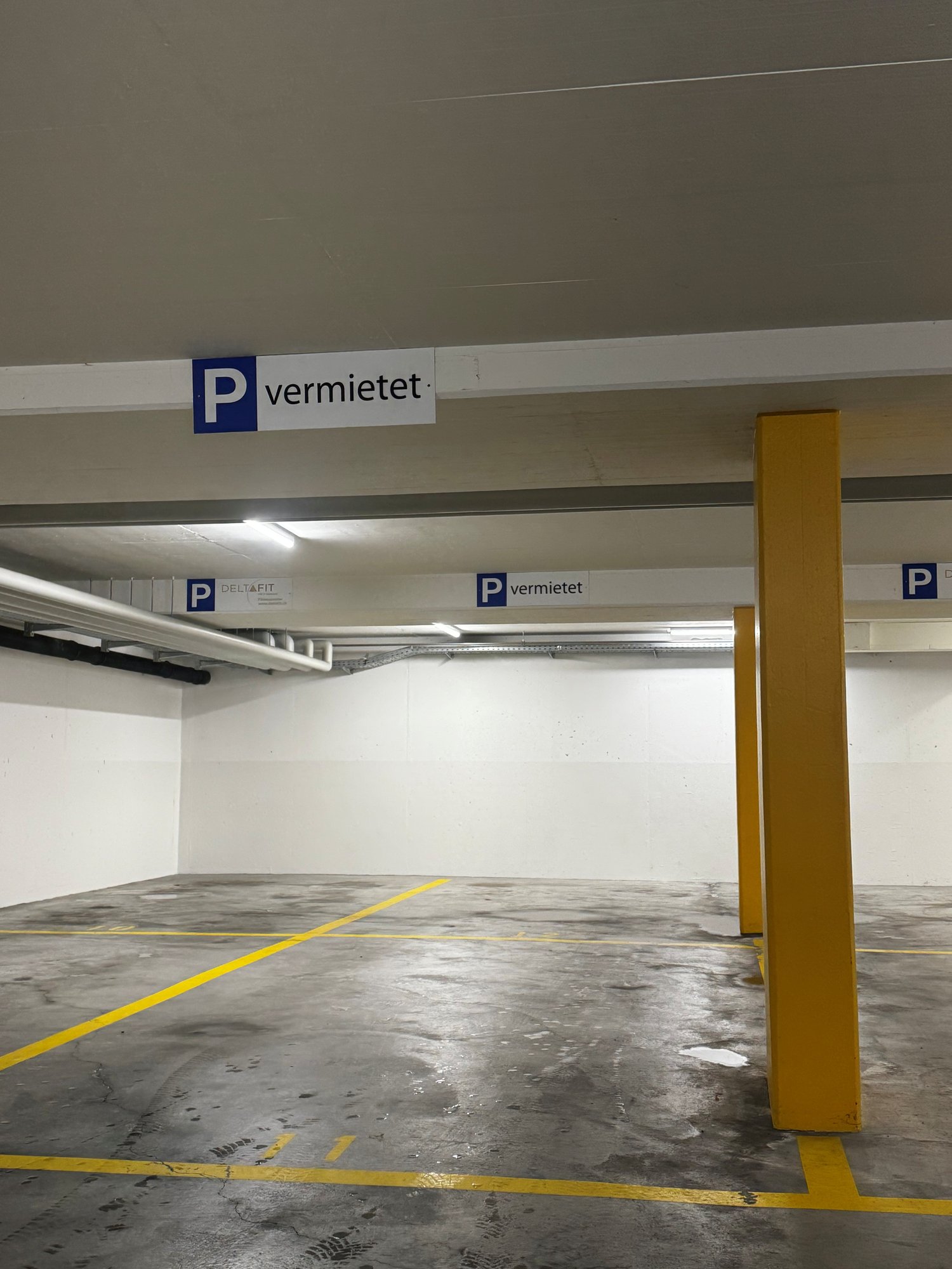 Empty parking lot with yellow lines, white walls, and yellow pillars.