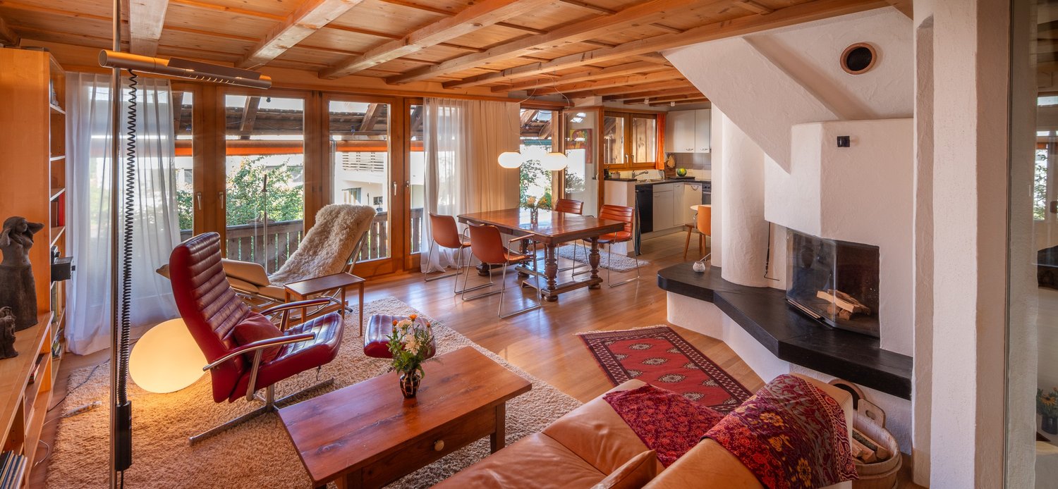 Living room with fireplace, couch, table, chair, wood floor, rug, windows