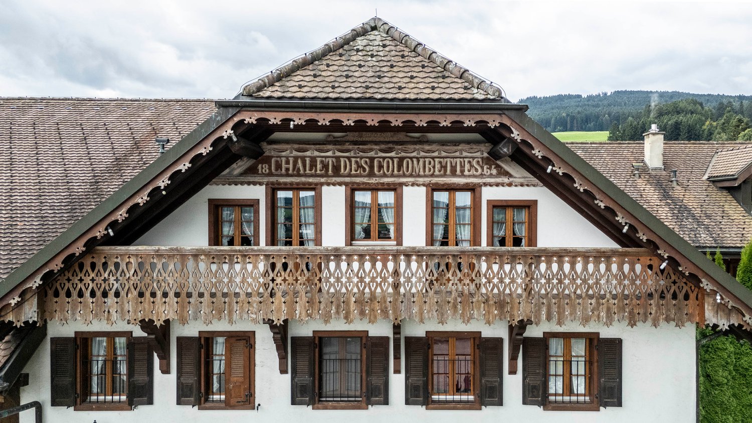 Facade of a chalet with an upper terrace supported by wooden structures and various windows