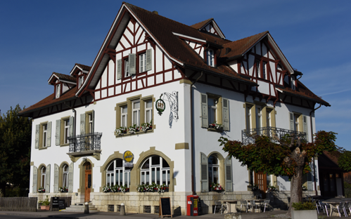 3 story house, white walls, brown roof, brown trim, arched windows, balconies, flower boxes, outdoor seating