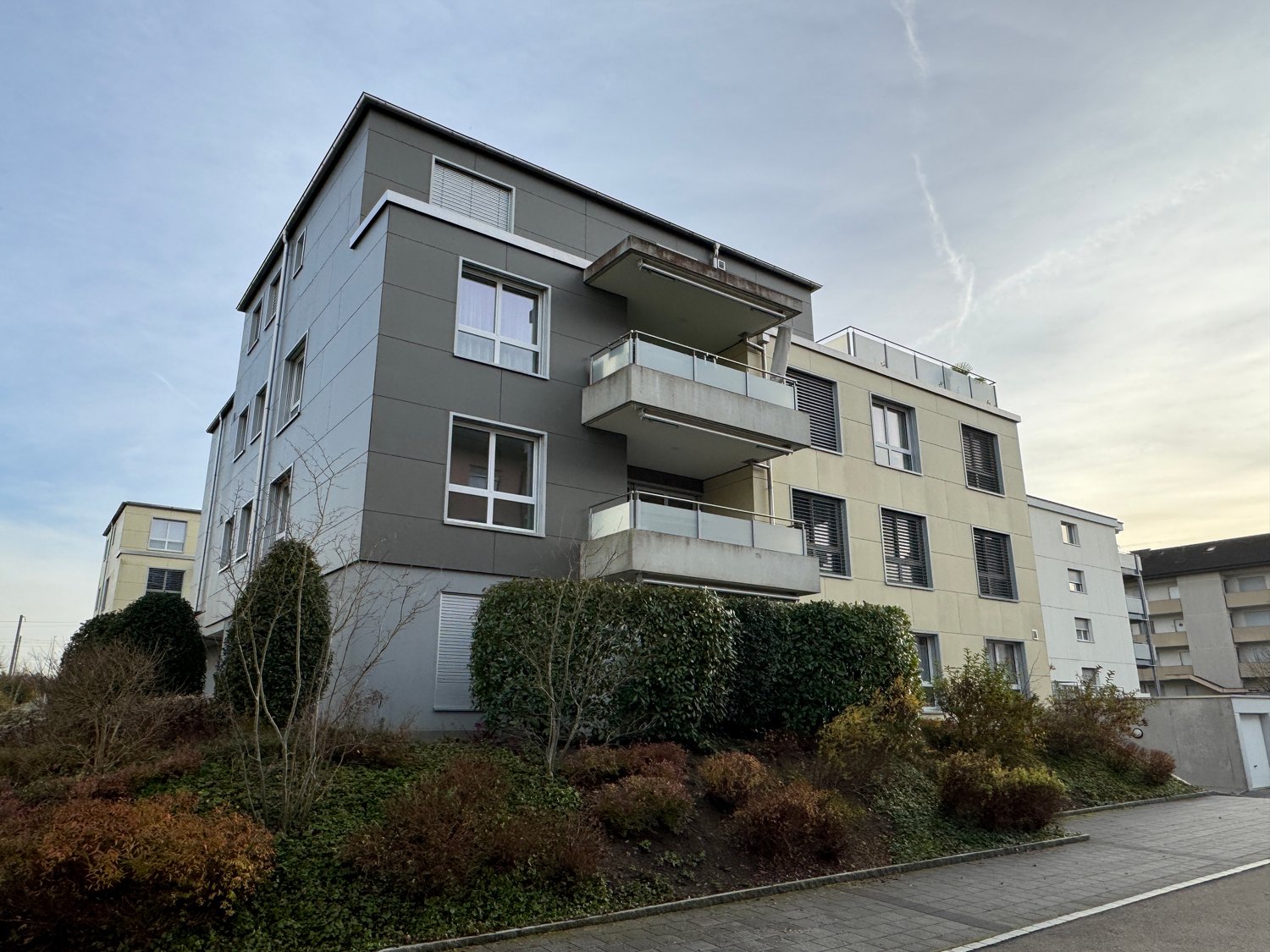 4-story building with balconies, modern architecture, well-maintained landscape