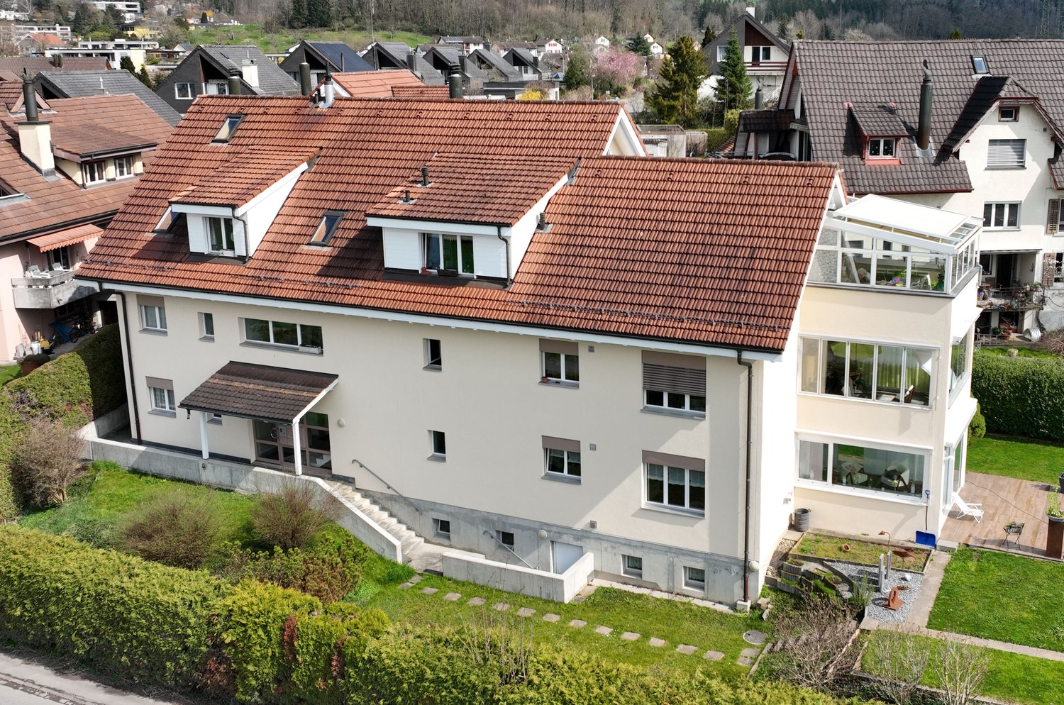 2 story house, beige exterior, brown roof, glass windows, green lawn, aerial view