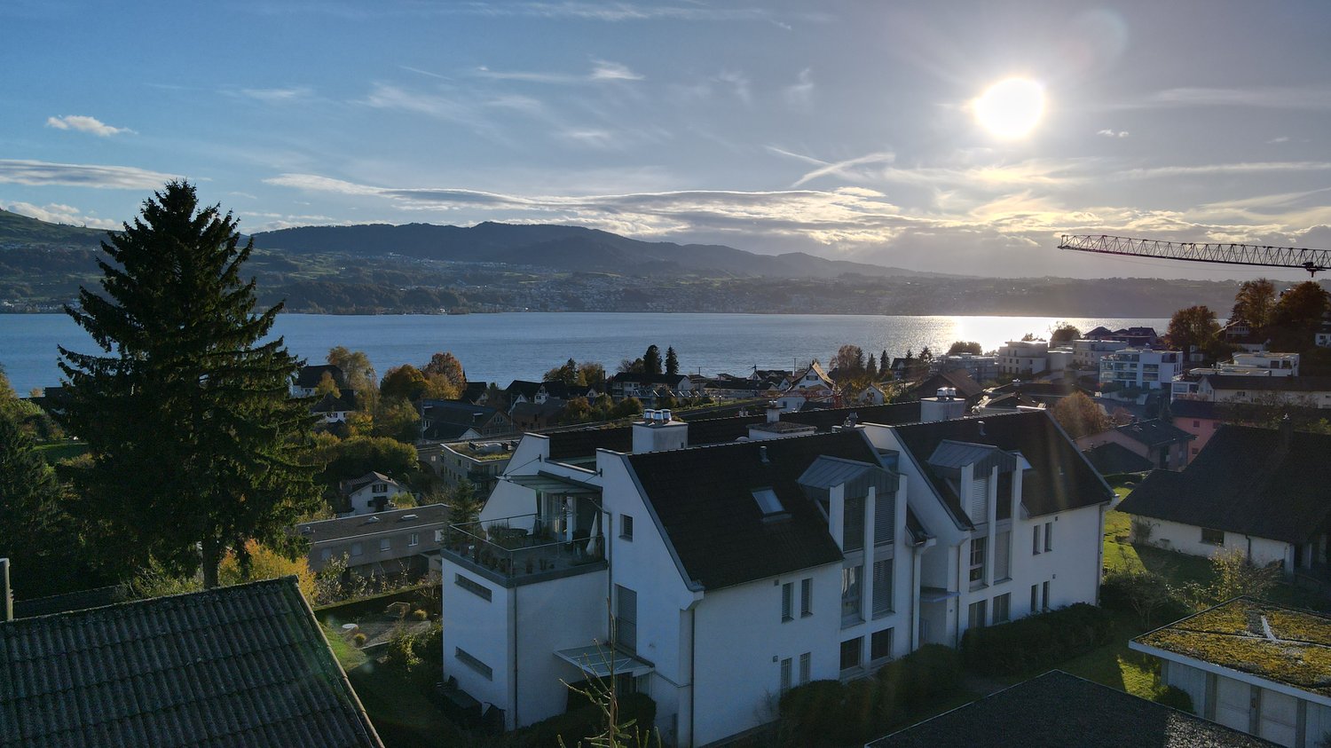 Modern white building with black roof, ground floor with balcony, mountain view, lake view