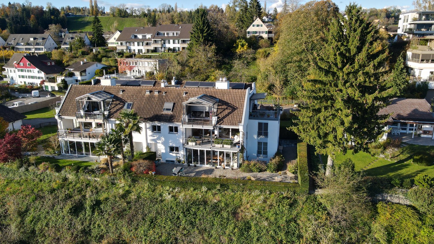 2 story house, brown roof, white exterior, large windows, balcony, pool, green grass