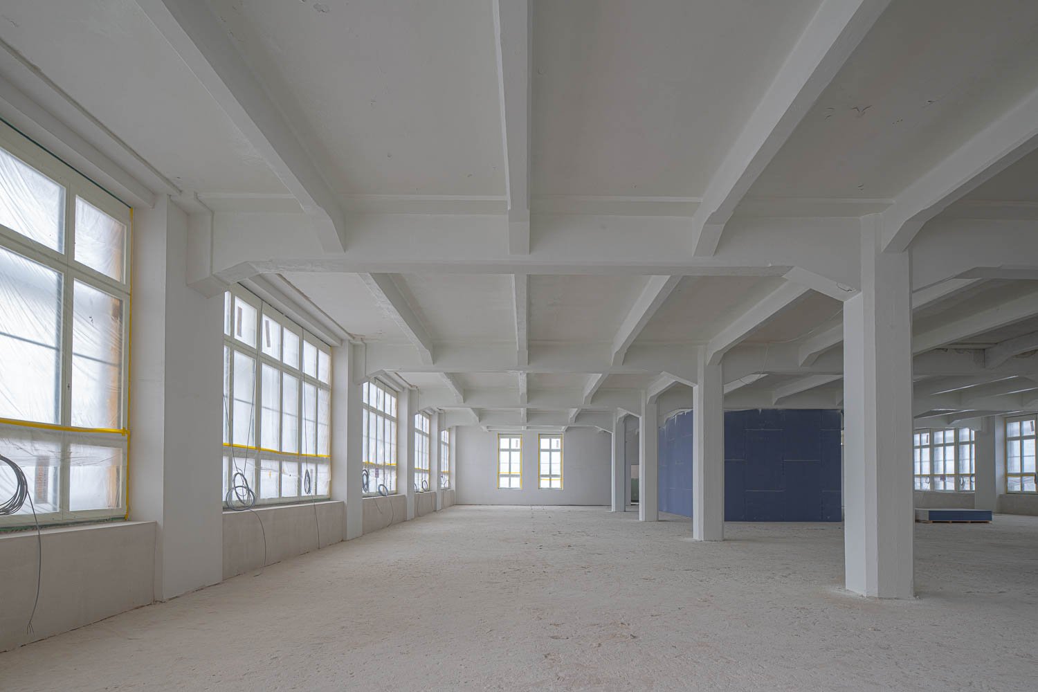 empty room, white walls, concrete floor, large windows, exposed beams, large open space
