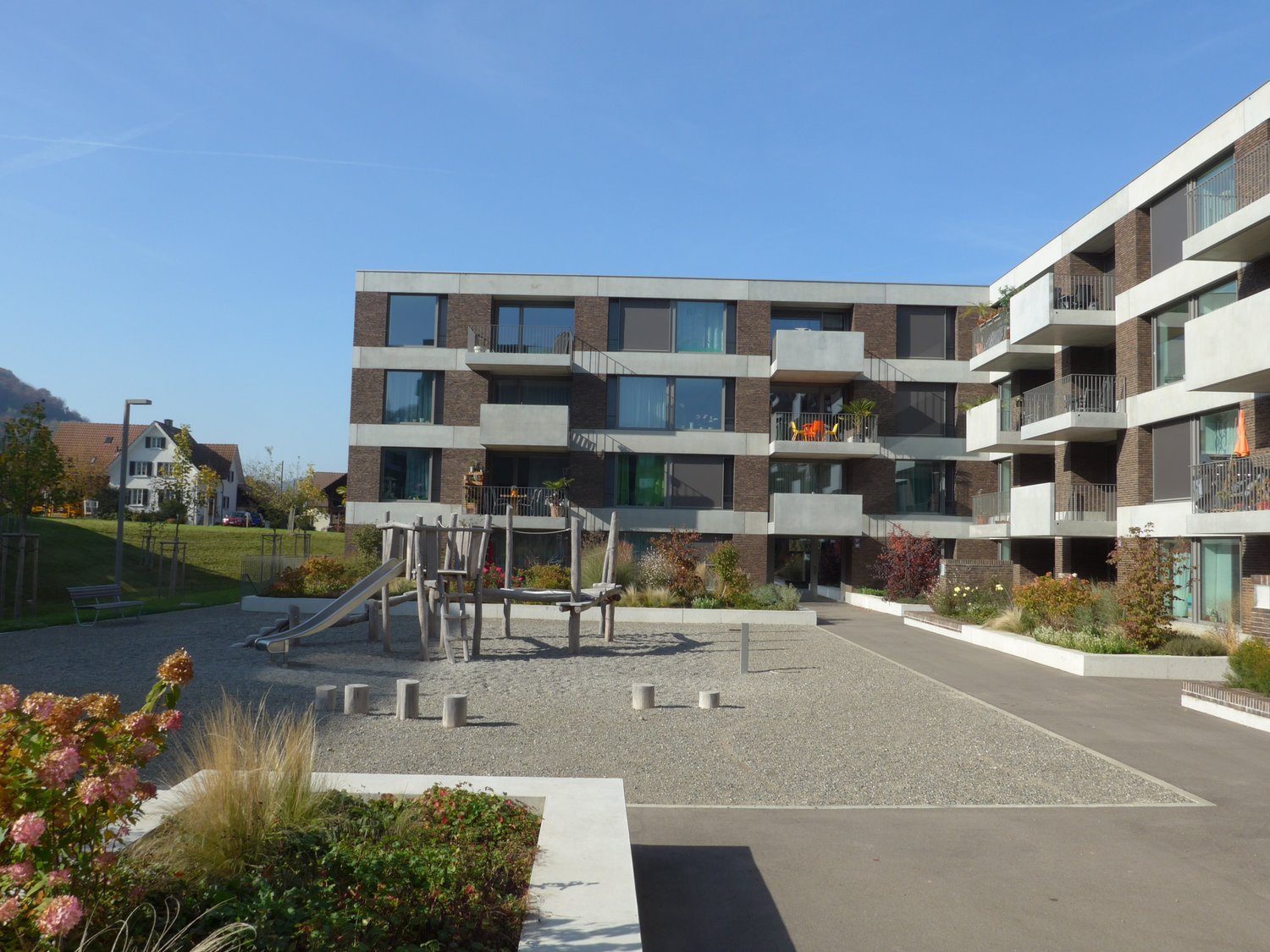 Large residential building, modern design, several balconies, garden, outdoor play area