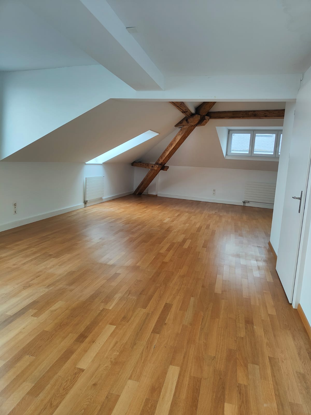 empty room, wooden floor, wooden beams, windows, radiators