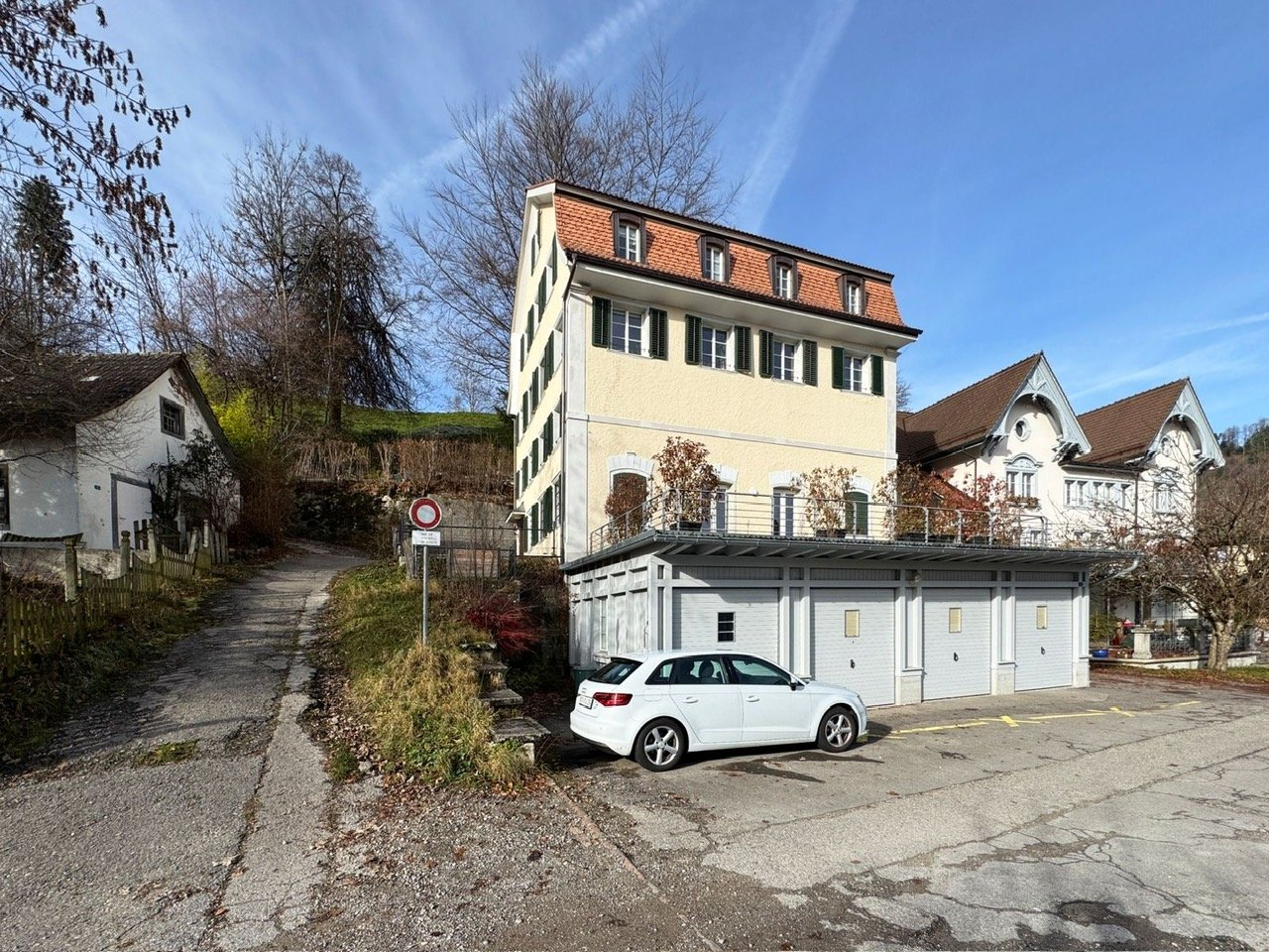 2-story house, yellow exterior, brown roof, 2 garages, parking lot in front, white car parked