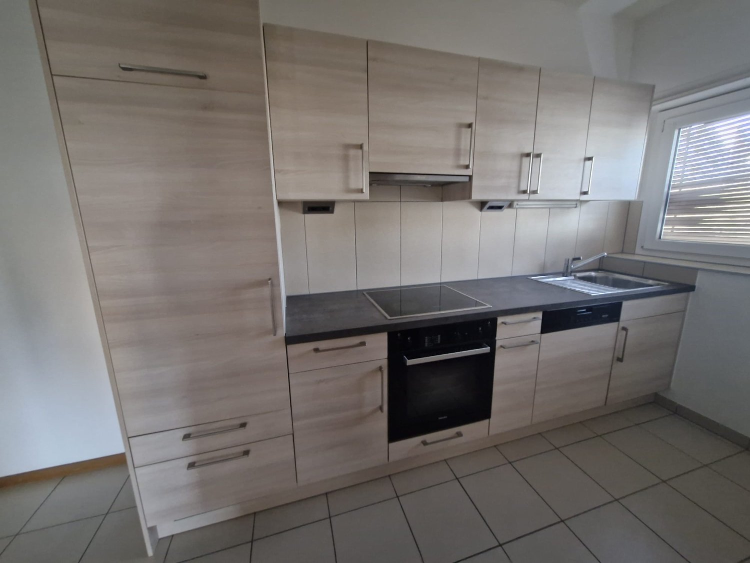 Light colored cabinets, stainless steel appliances, white tile flooring, window with blinds, overhead hood, open shelving