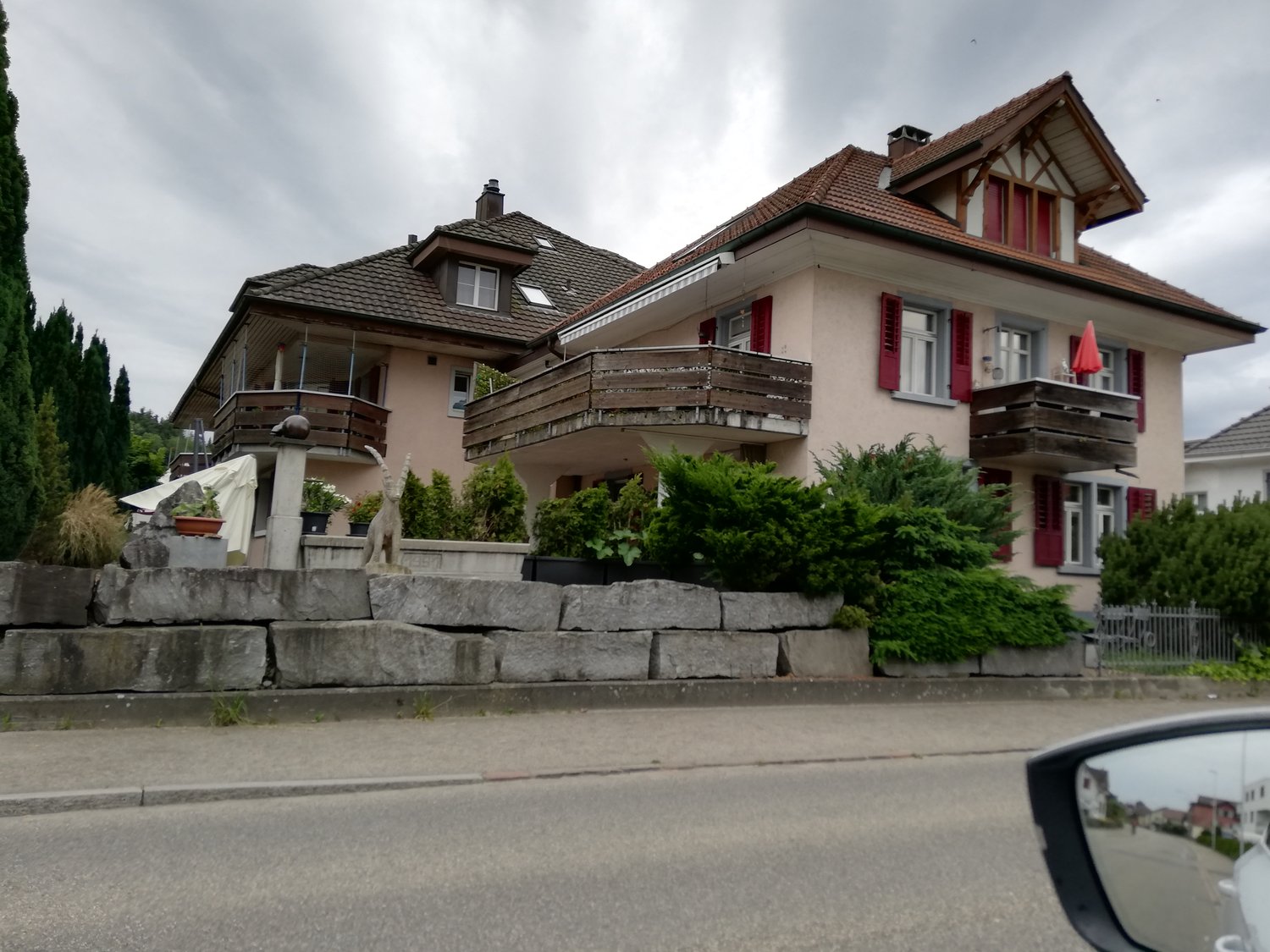 3 story house, red windows, wooden balcony, stone wall foundation, stone pavement