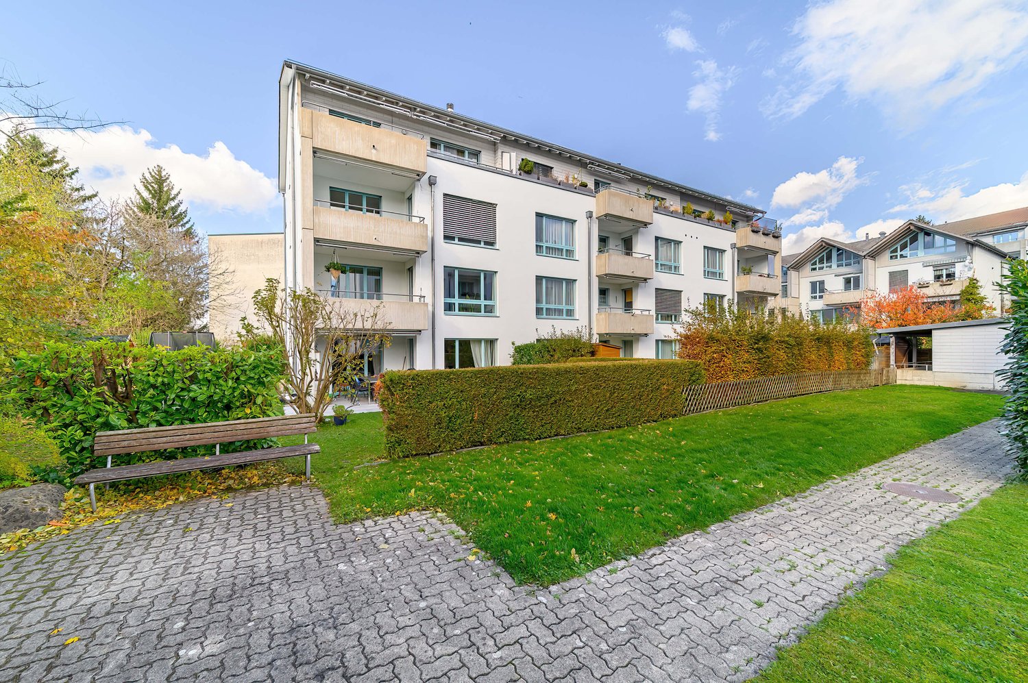 3 story apartment building, balconies on each floor, landscaped garden, paved path