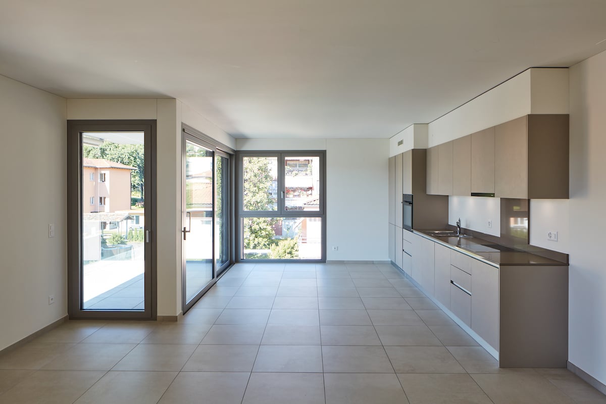 empty room, large windows, sliding glass doors, tiled floor, kitchen area
