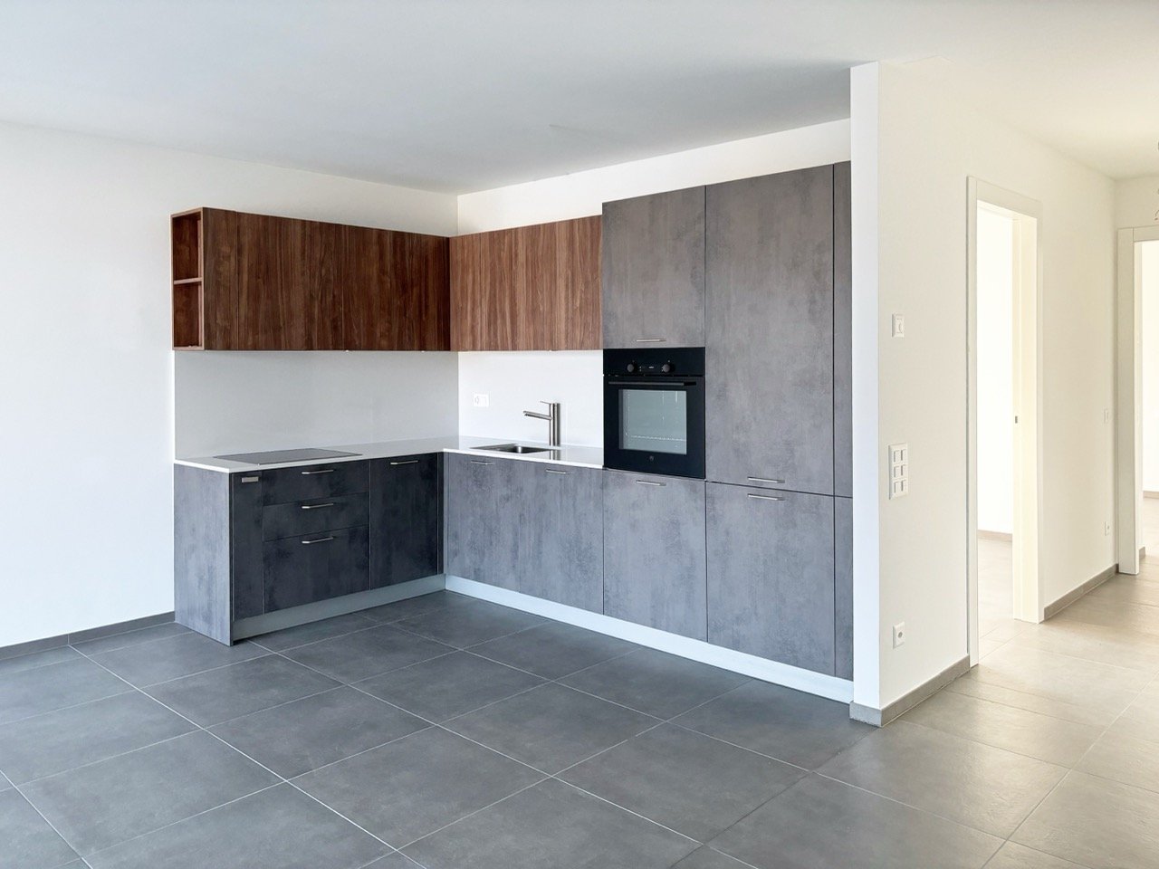 modern kitchen with gray cabinets, white countertops, black oven, wooden shelves, tiled floor