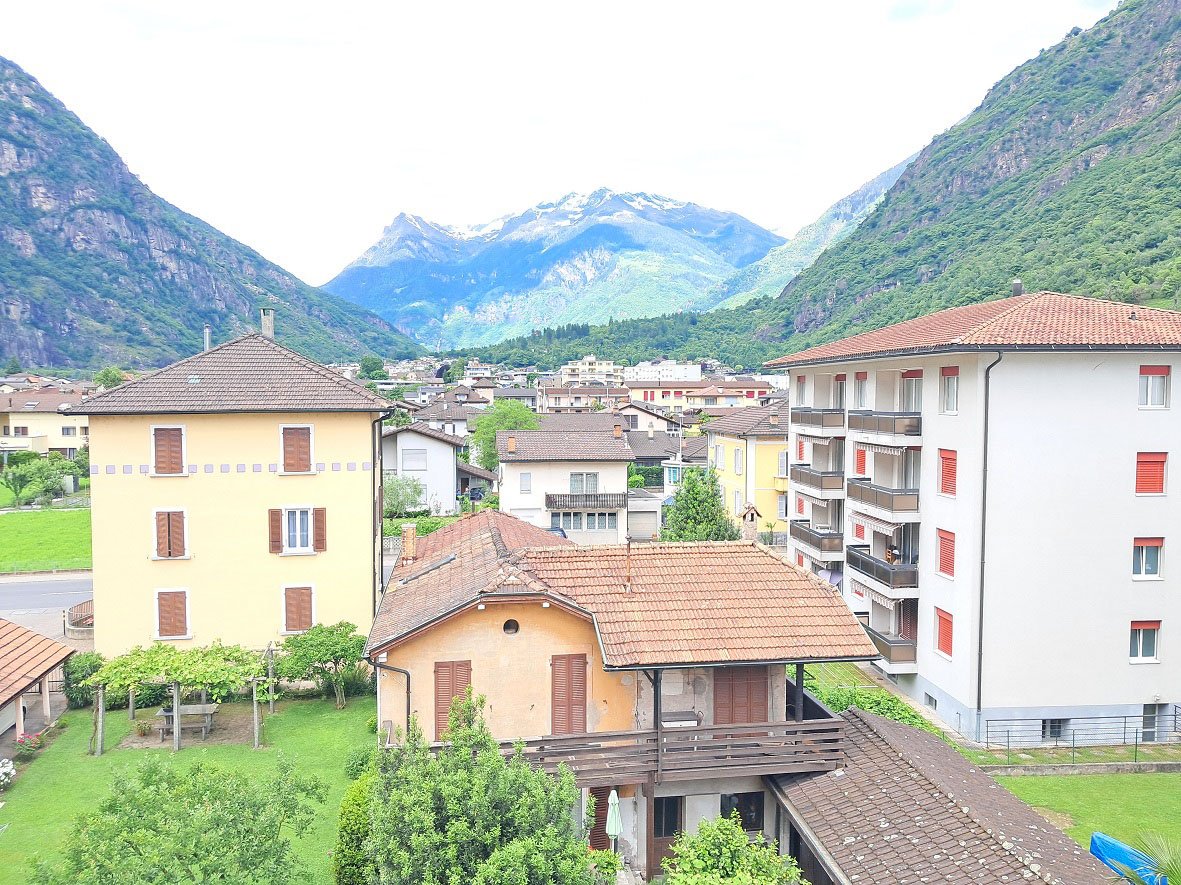 small town, several buildings, green grass, trees, mountains in the background