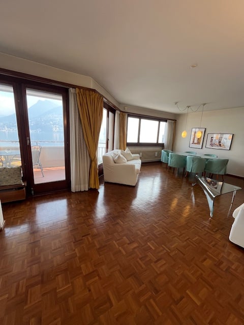 Living room, wooden floor, balcony, glass windows, dining table, white sofa