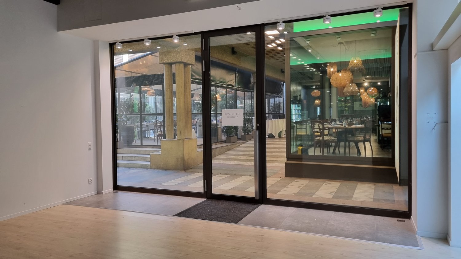 glass doors, wooden floor, white walls, plants, tables, chairs, lamps