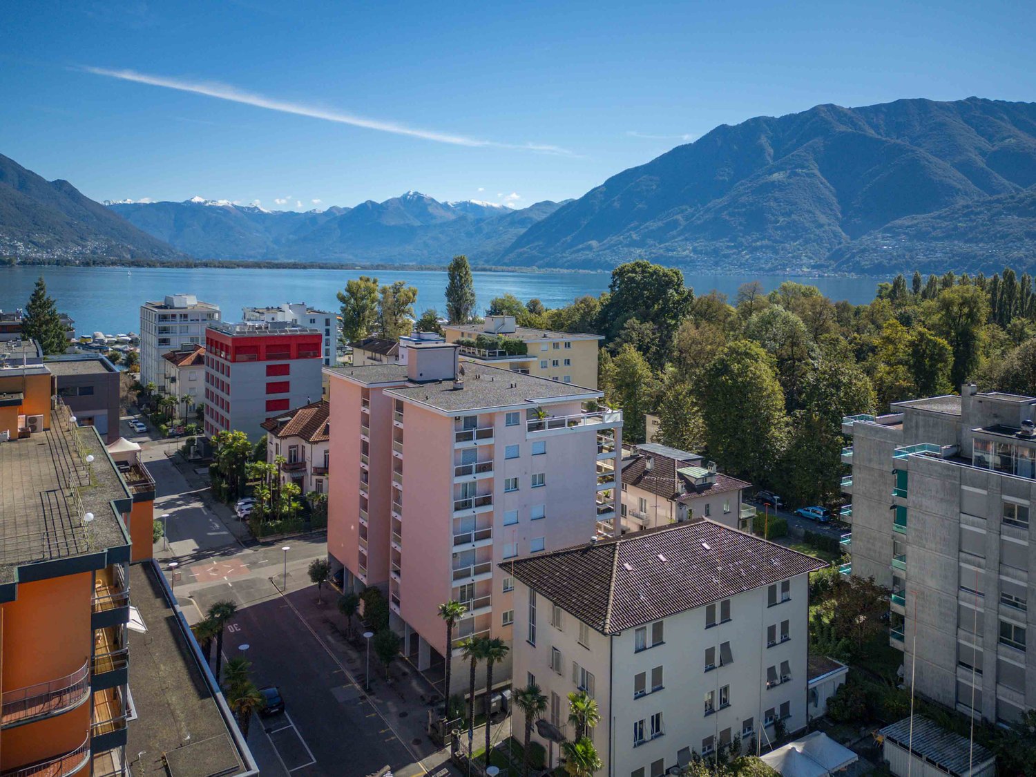 Aerial view of several buildings with mountains and a lake in the background.