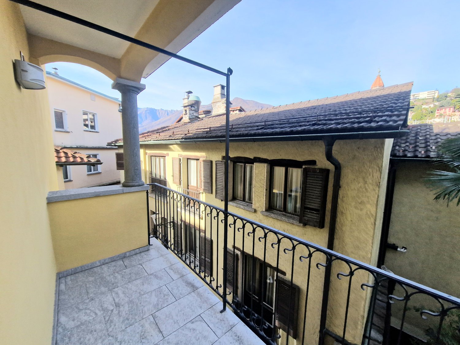 Terraced balcony with black railings, paved floor, a pillar and a light fixture