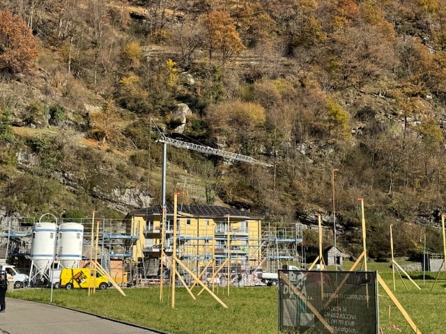Building under construction, steel scaffolding, solar panels, yellow building, tanks, road