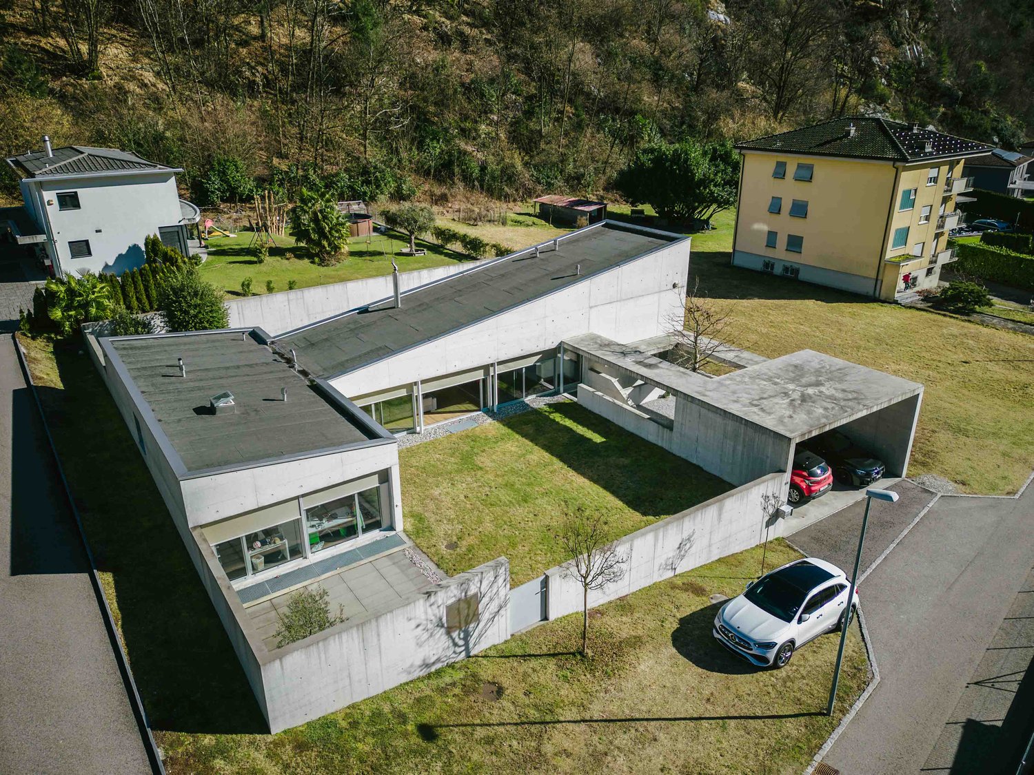 modern house, multiple levels, covered parking, front garden, trees, white exterior