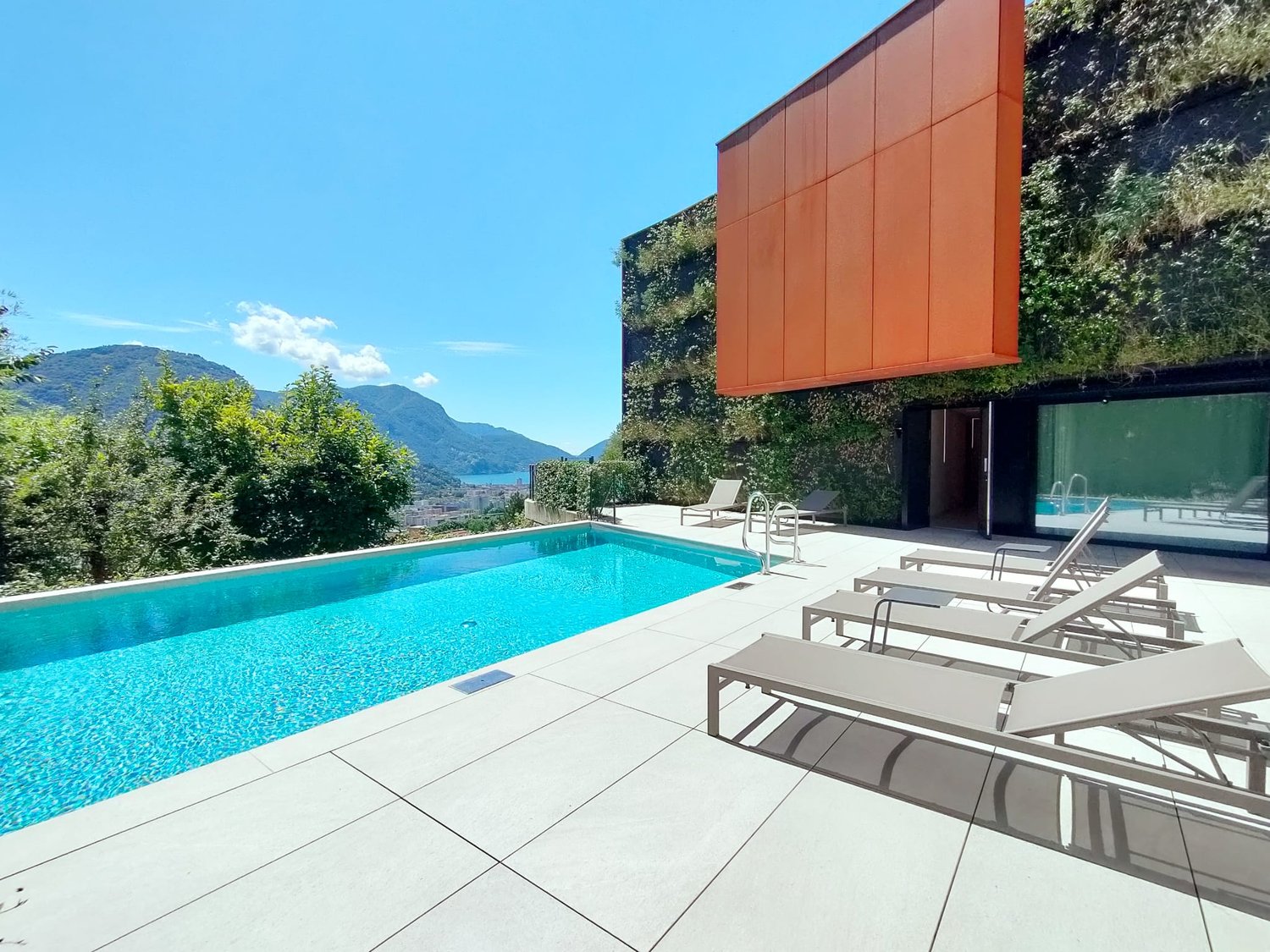 Modern architectural design, outdoor swimming pool, lounge chairs, white tile flooring, green wall, pool handrail