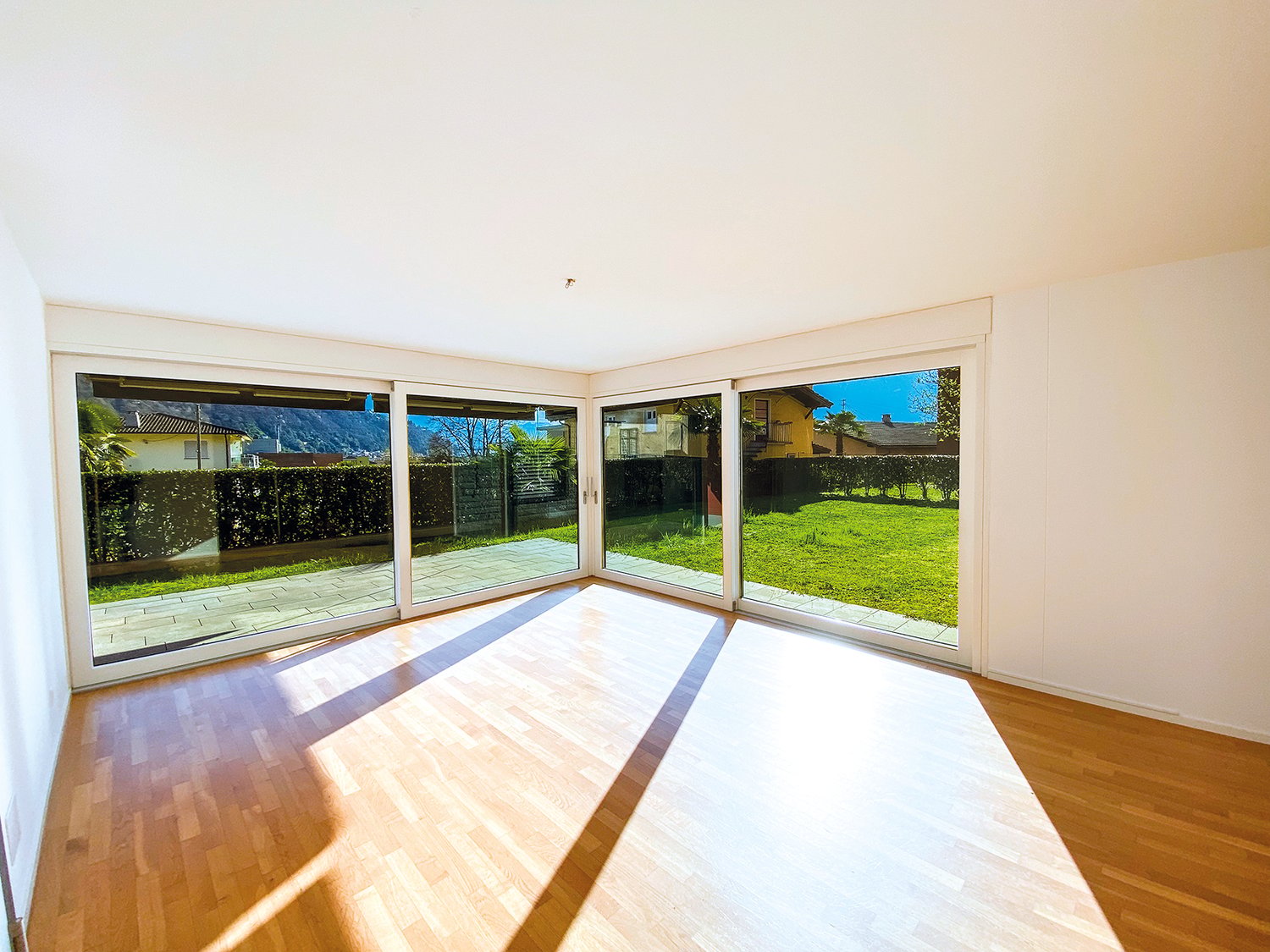 large windows, wooden floor, white walls, view of a garden