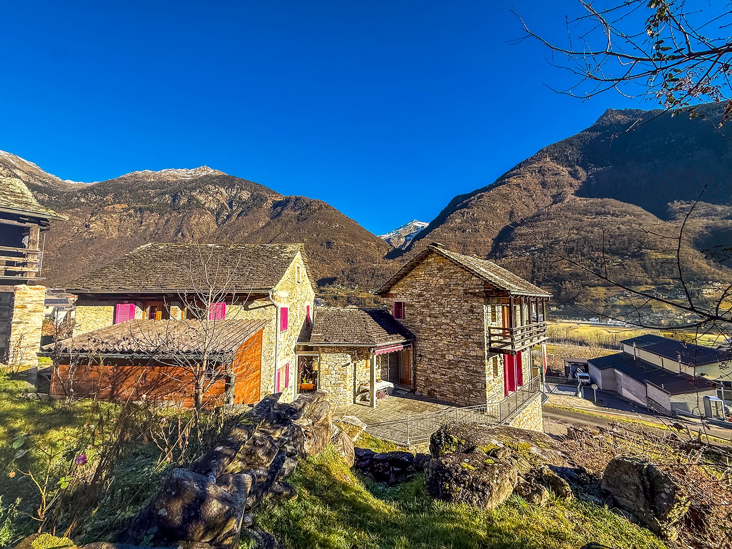 Stone house, red windows, located on a hill, elevated ground floor, mountain view
