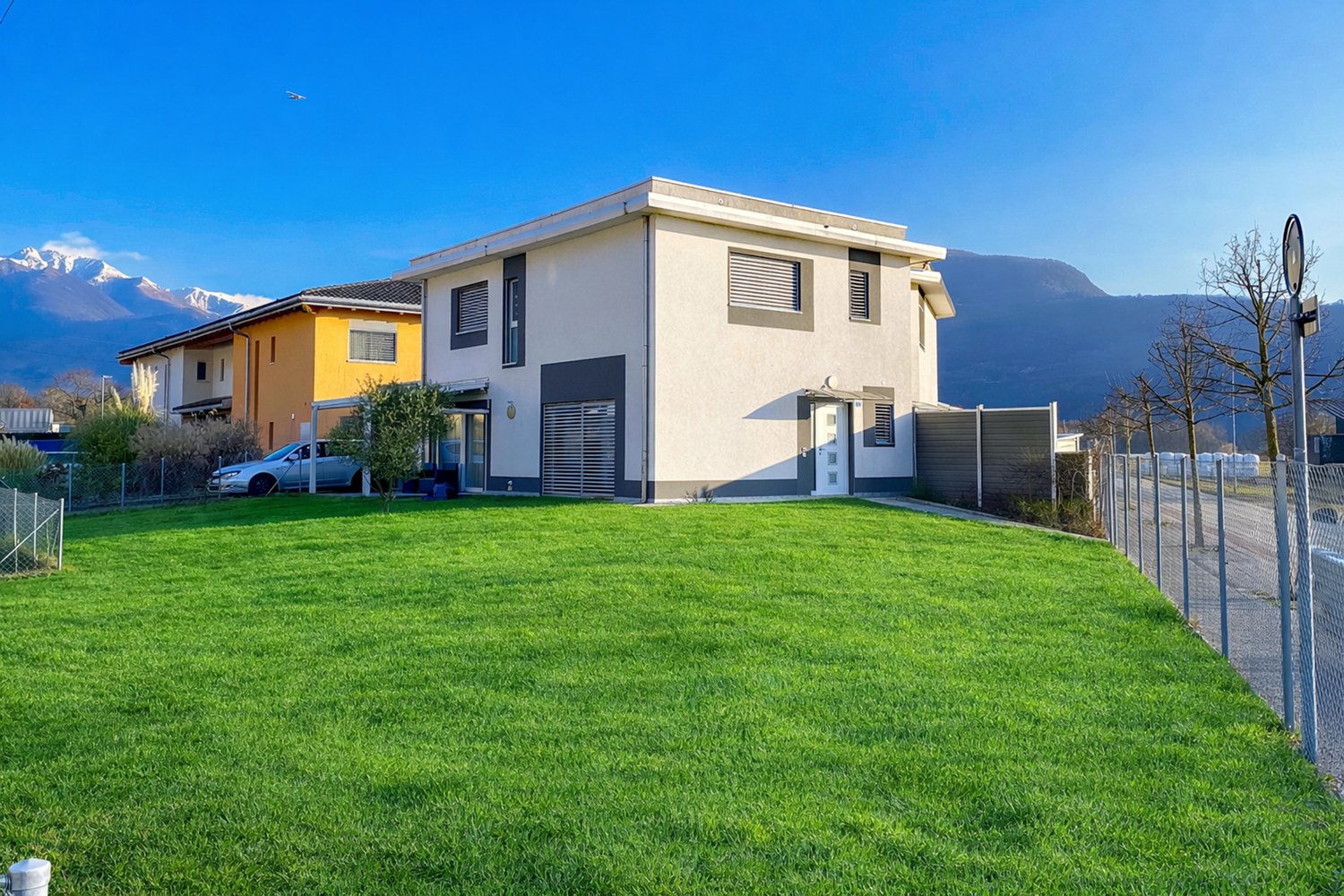2 story house, white exterior, grey trim, large windows, garage, large grassy yard, mountains in background