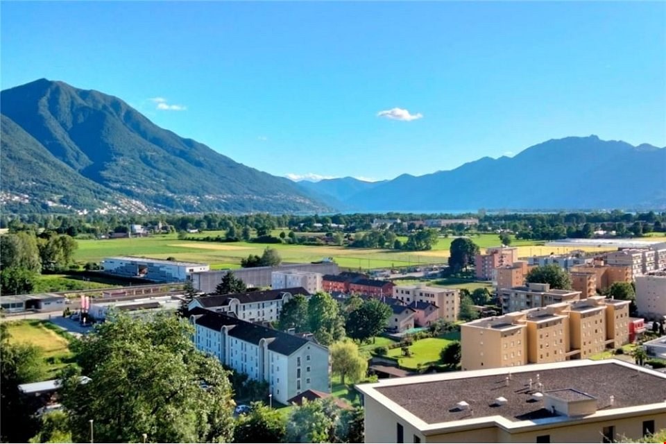 Panoramic aerial view of town with green fields and mountains