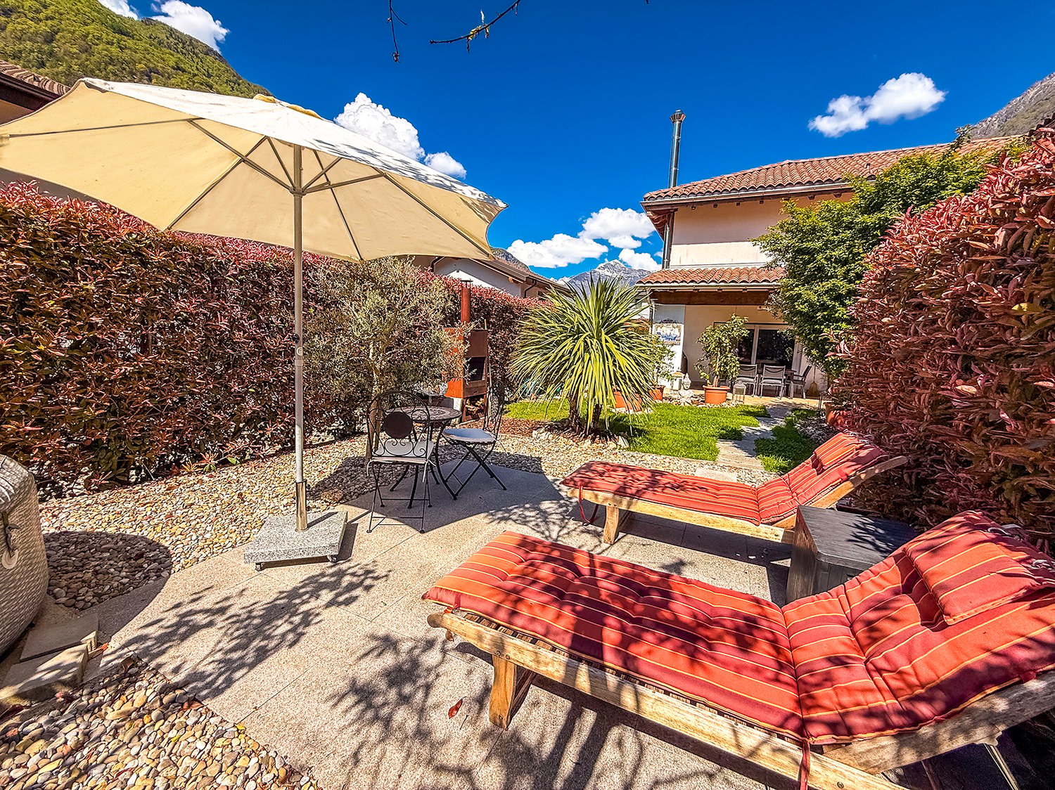 outdoor area with loungers, patio umbrella, small table, mountain view