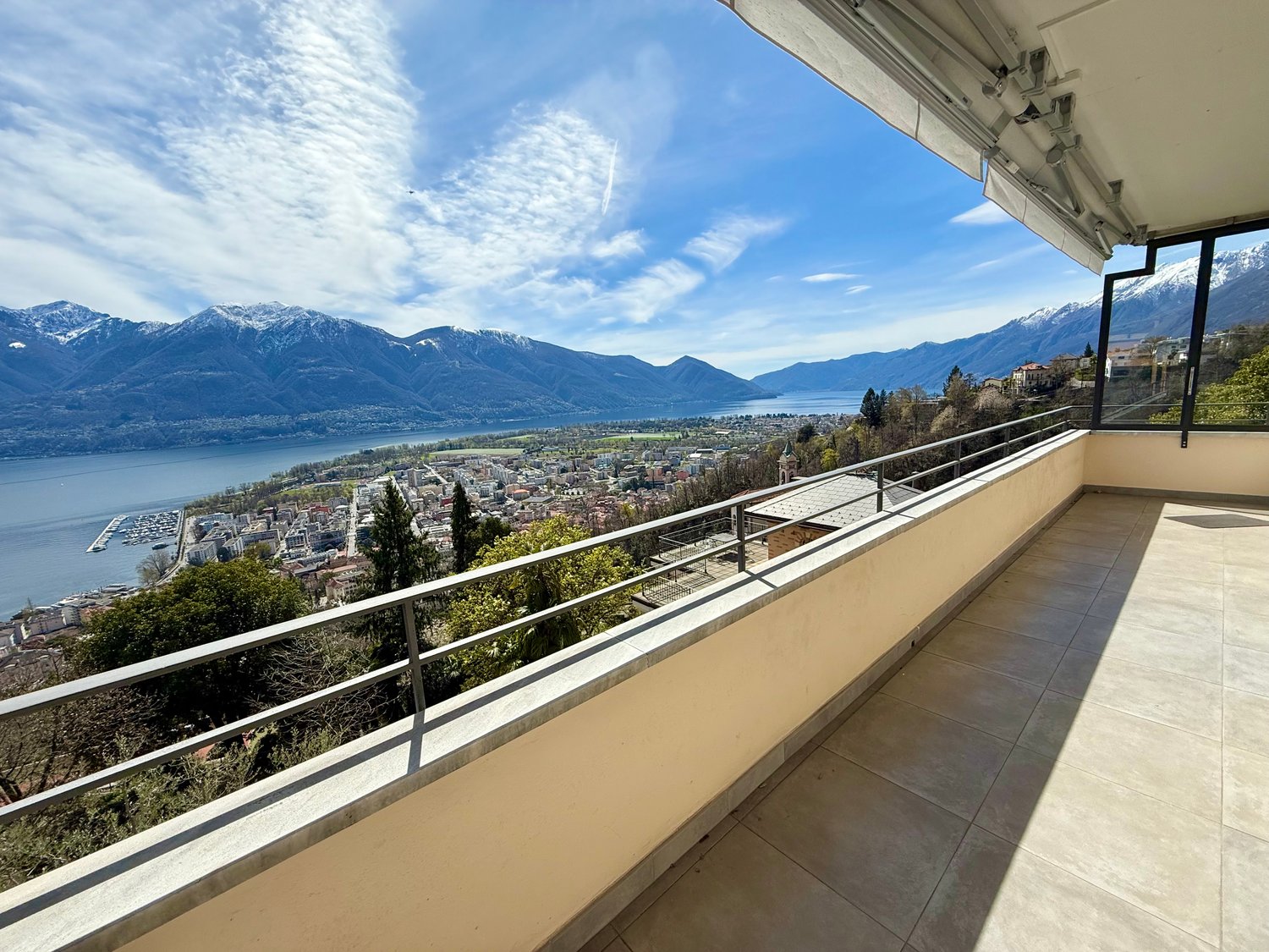 large balcony with metal railings, tiled floor, panoramic view of mountains and lake