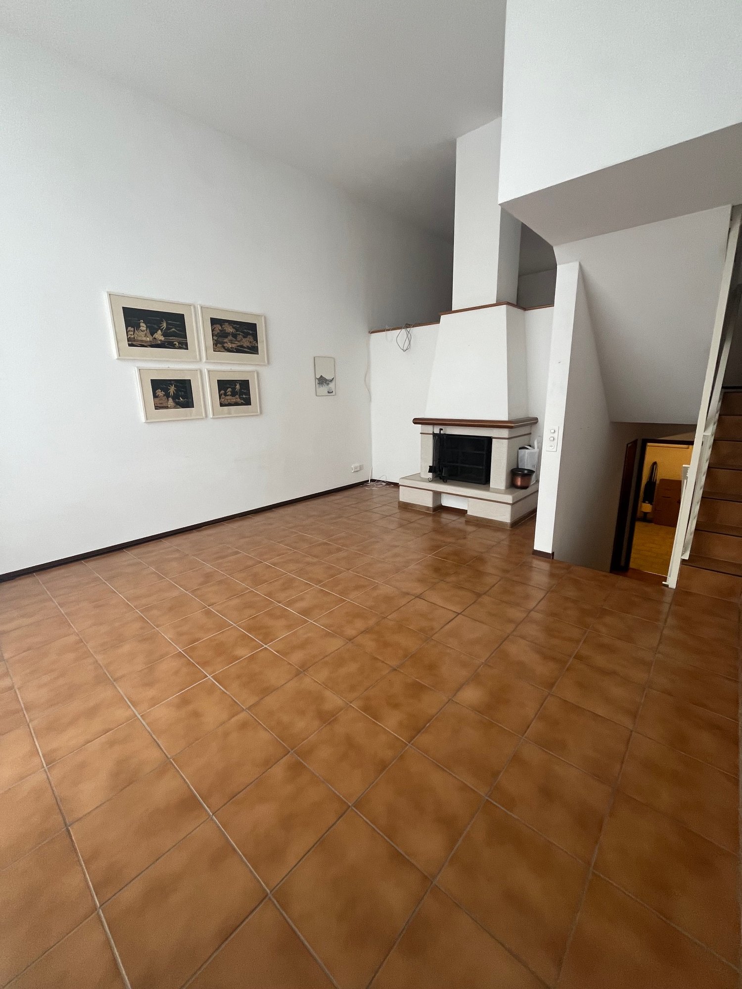 white walls, brown tiles, fireplace, staircase, artwork